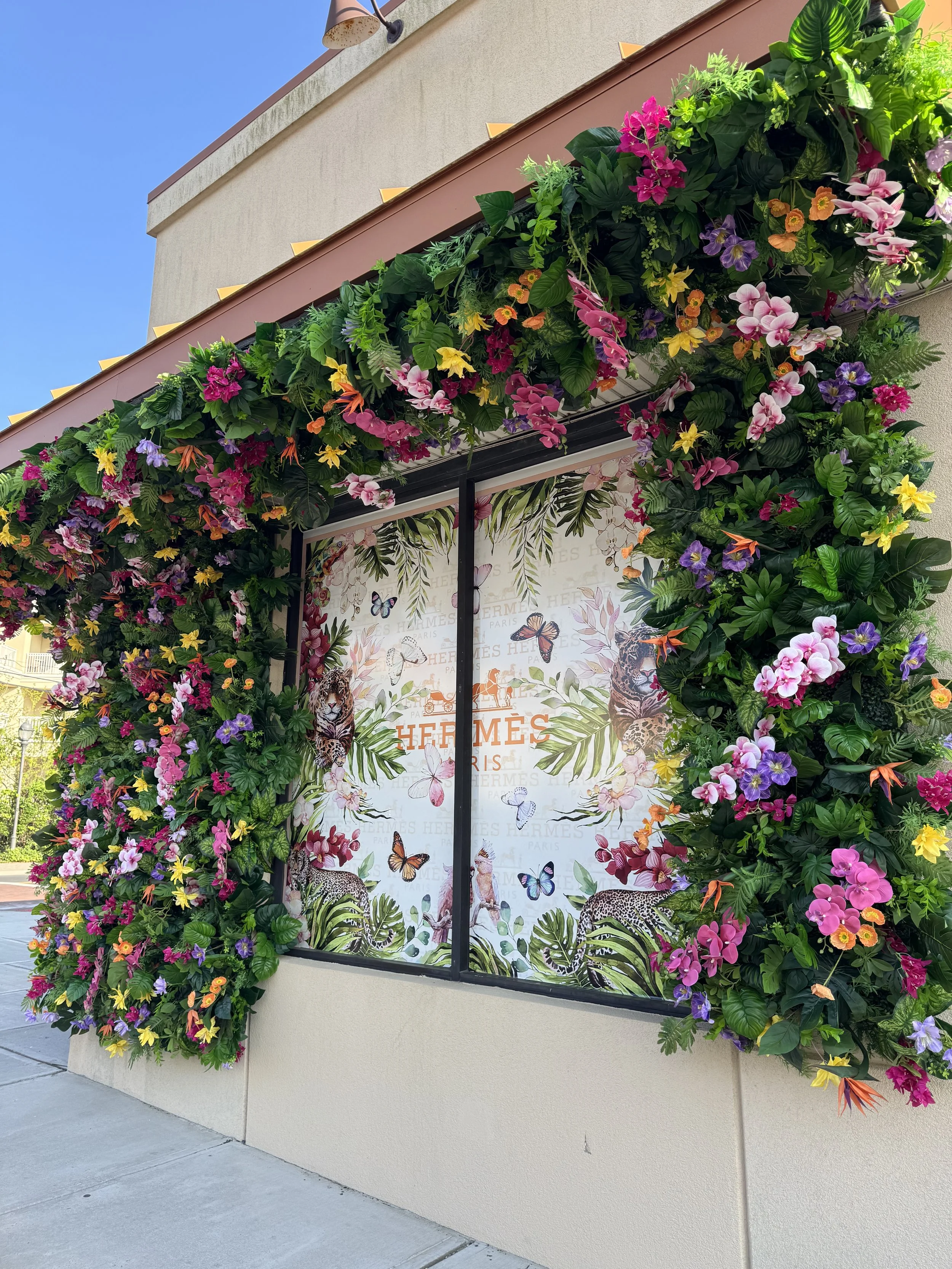 Boutique storefront framed in permanent orchids, roses and tropical greenery, a permanent floral installation by Blooms by Lily