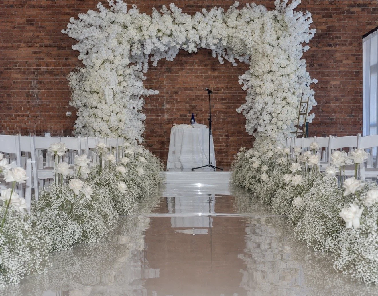 Custom chuppah and white floral aisle against brick walls at a wedding in Montclair, NJ, by Blooms by Lily