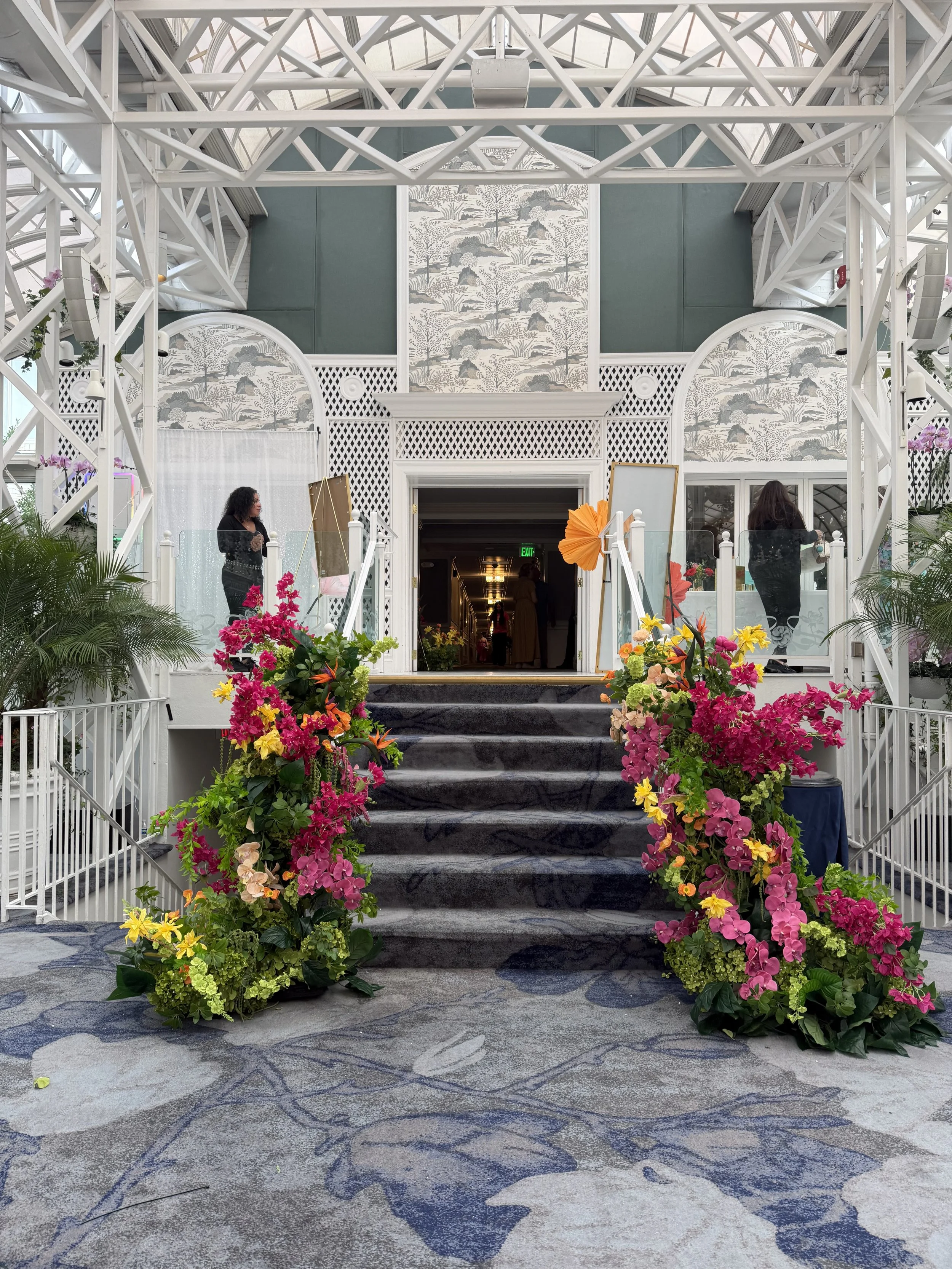 Fresh flower stair wrap in pink, magenta and green framing the conservatory staircase at The Madison Hotel, designed by Blooms by Lily