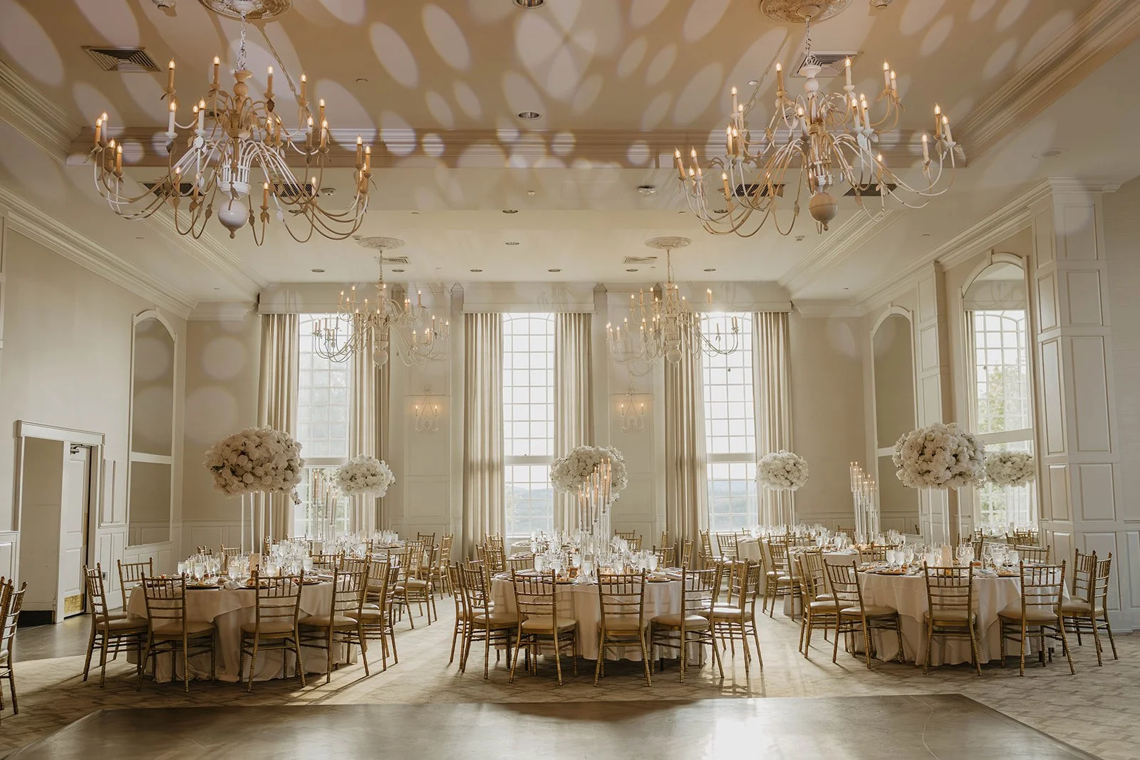 Elegant event hall decorated with large floral centerpieces, chandeliers, and round tables set for a wedding or formal gathering. At crystal springs candelabras and tall centerpieces and candle design