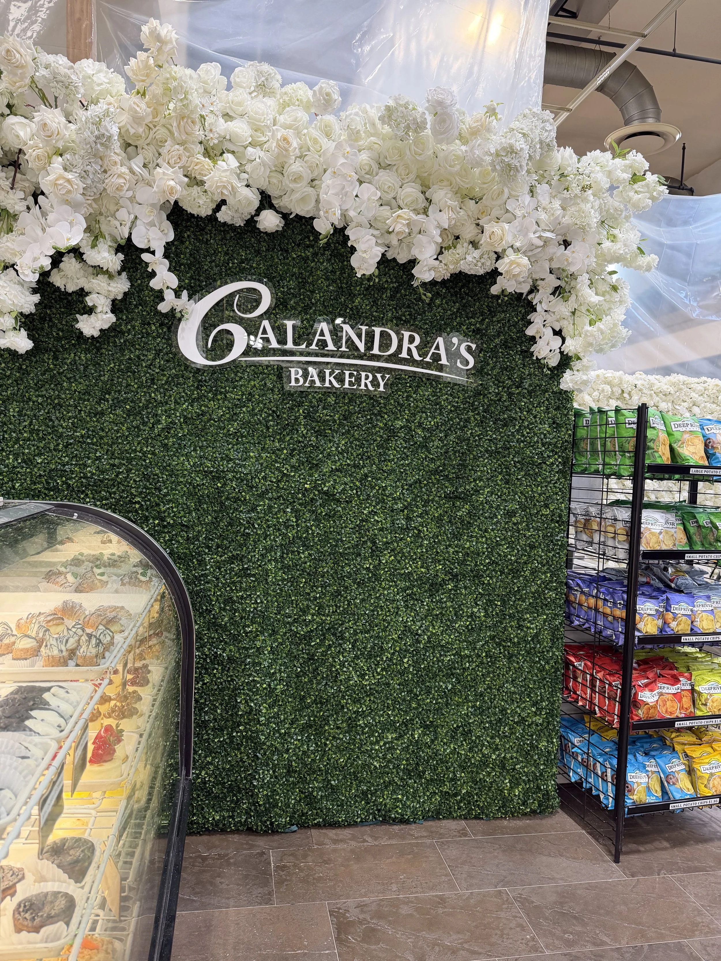 Boxwood logo wall with white blooms for an in-store display
