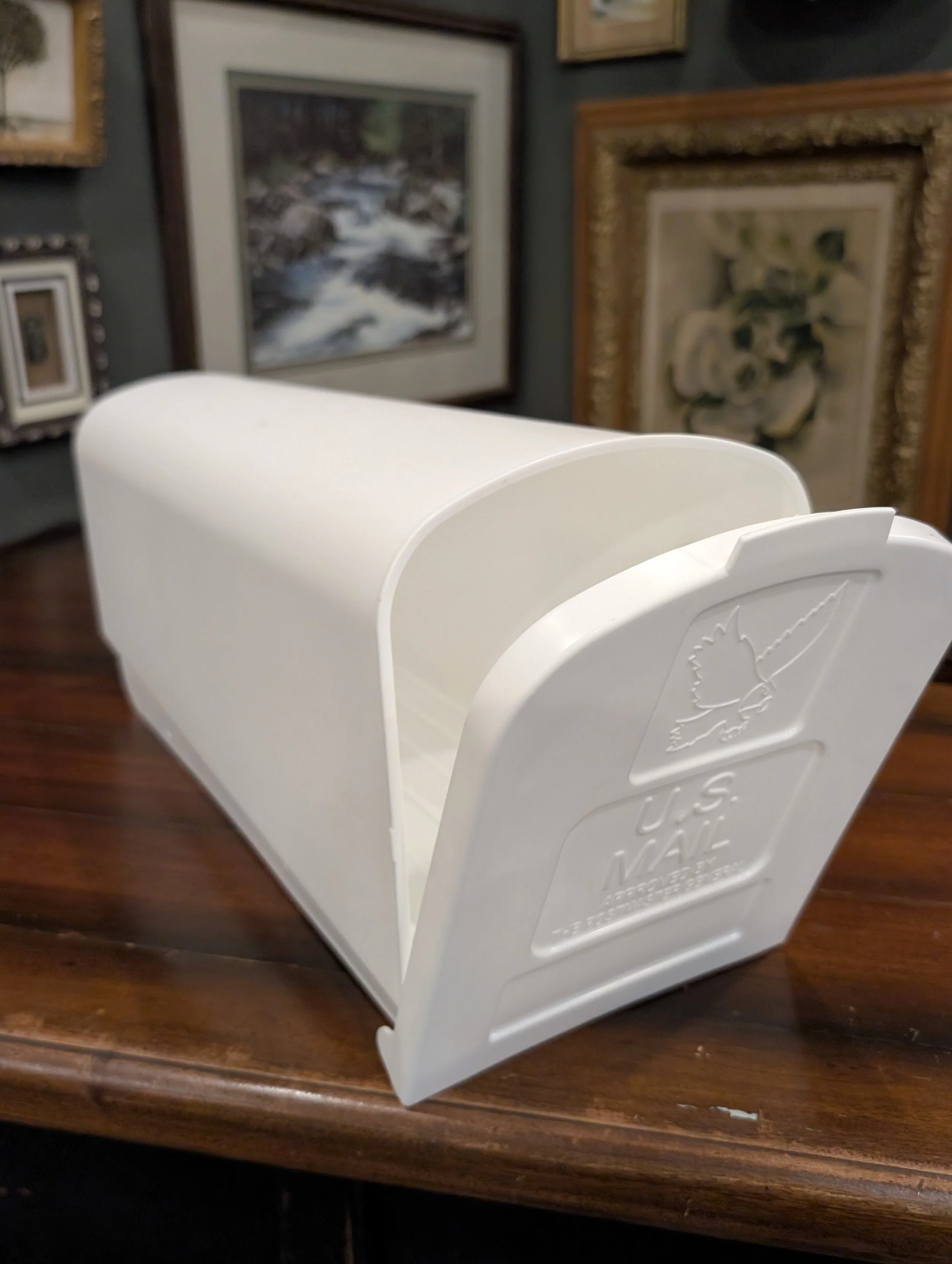 White mailbox (plastic). Can be used as a card box or used for notes/postcards written by guests.