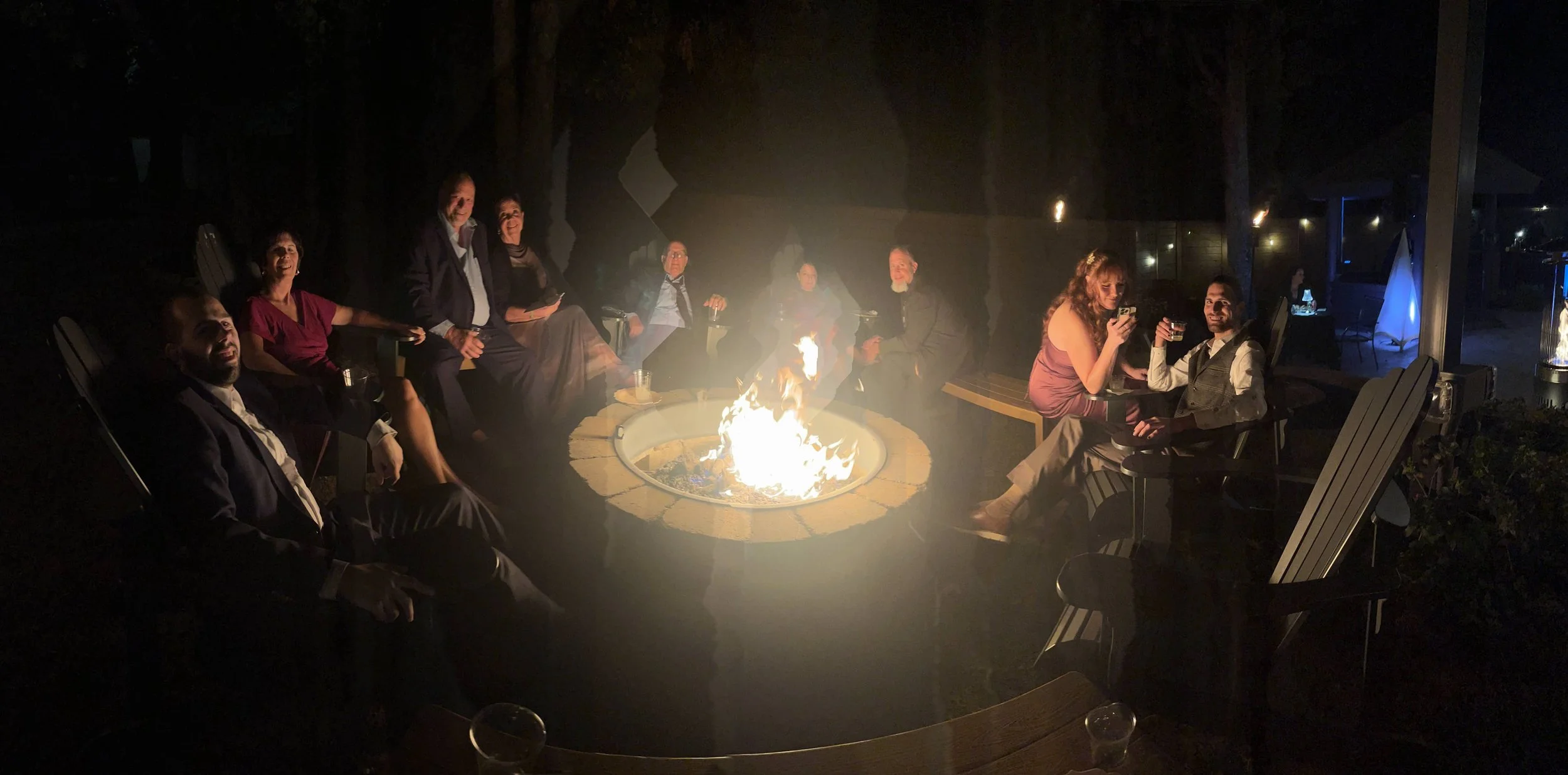 Stone gas firepit with people sitting around at night at Timber Rock Lodge