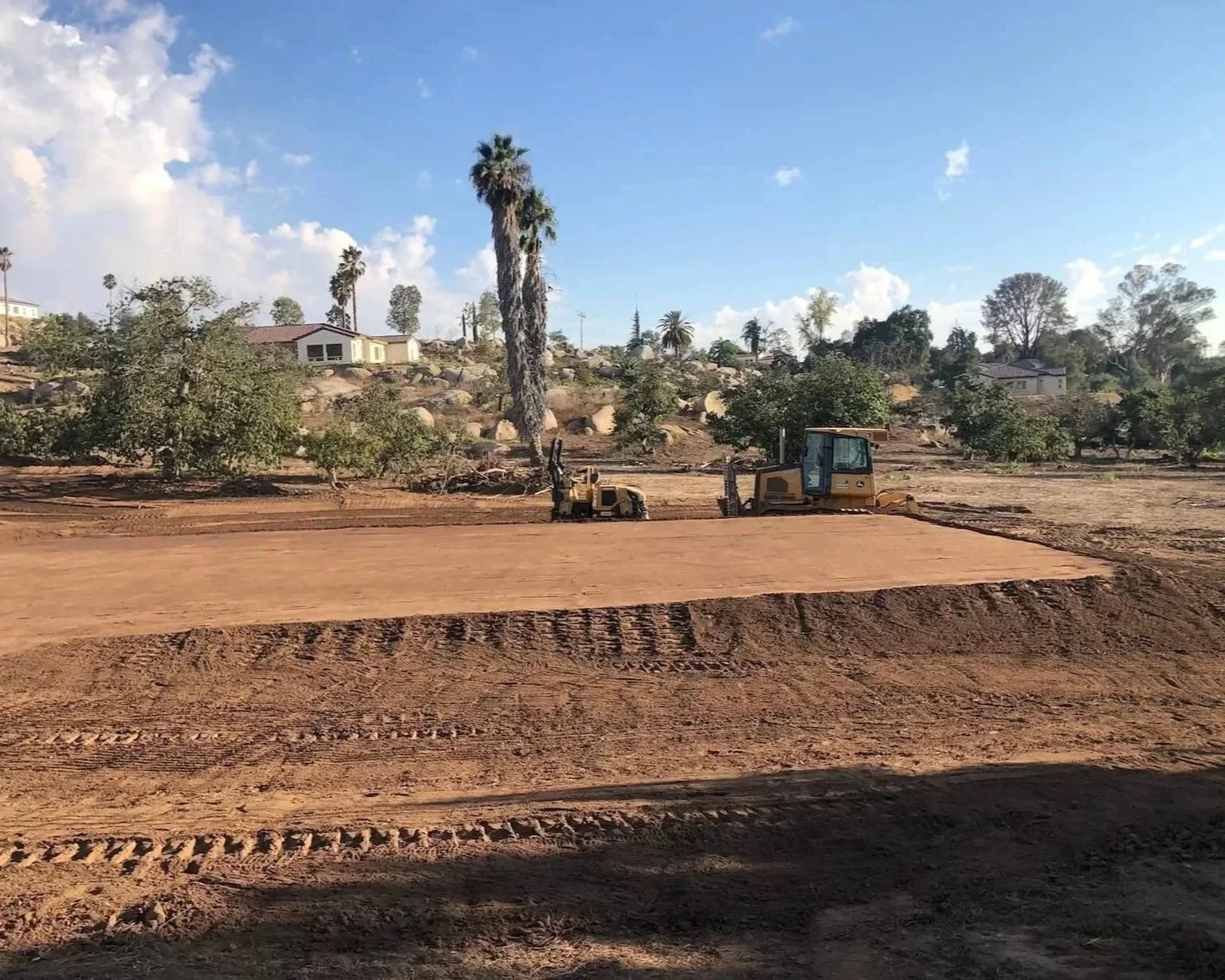 finished grading for an ADU pad with construction trucks parked on site