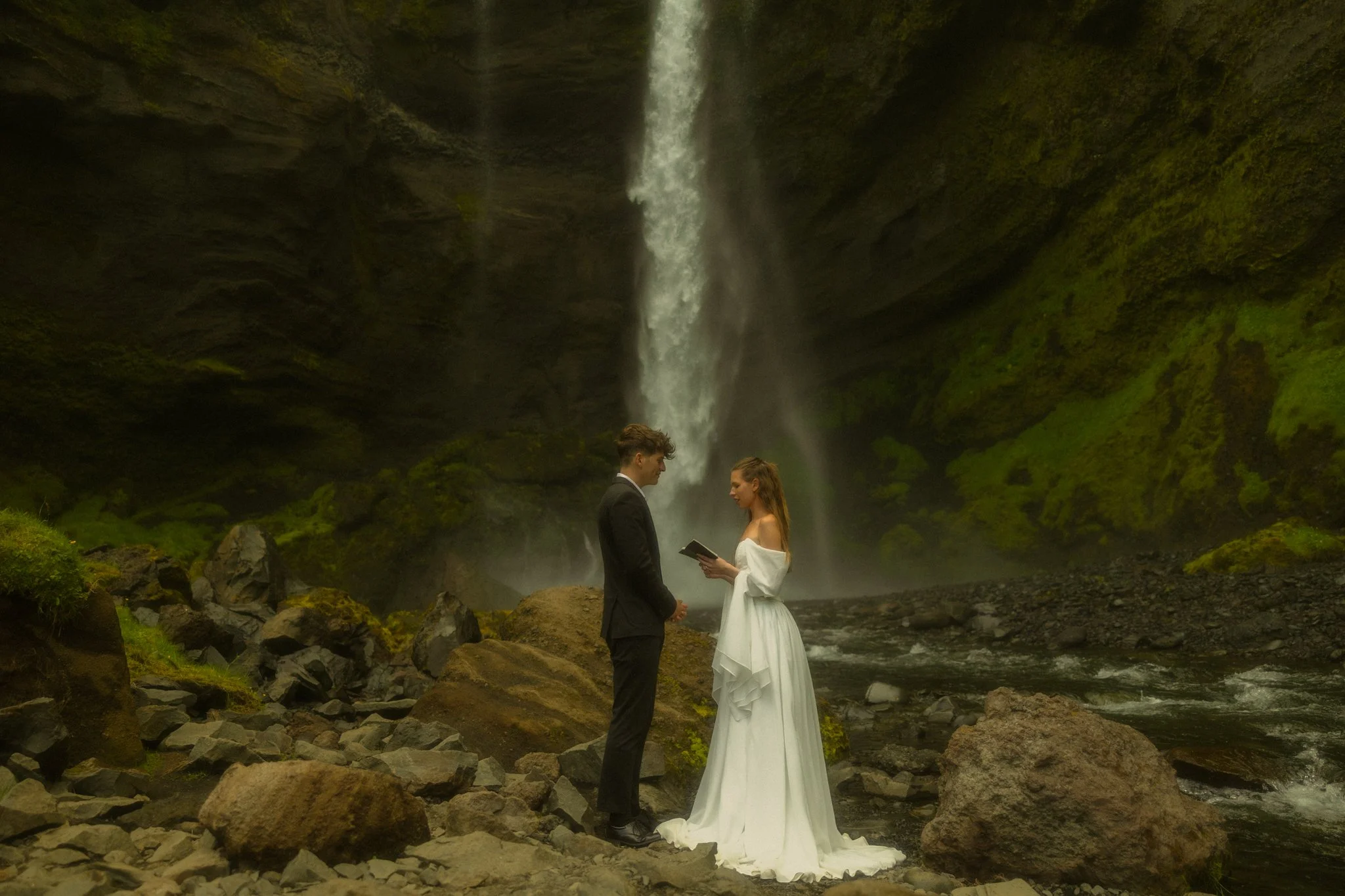 a couple exchanging their vows under a waterfall along the south coast of Iceland