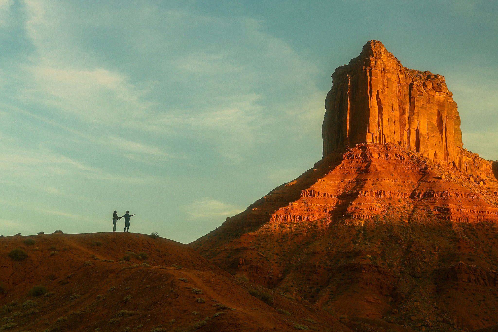 a couple pointing at large red rock formation in Moab Desert
