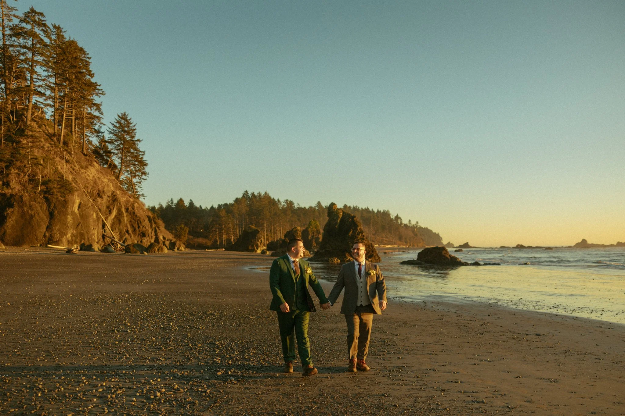 a LGBTQ+ couple walking on a beach in Olympic National Park for their winter elopement