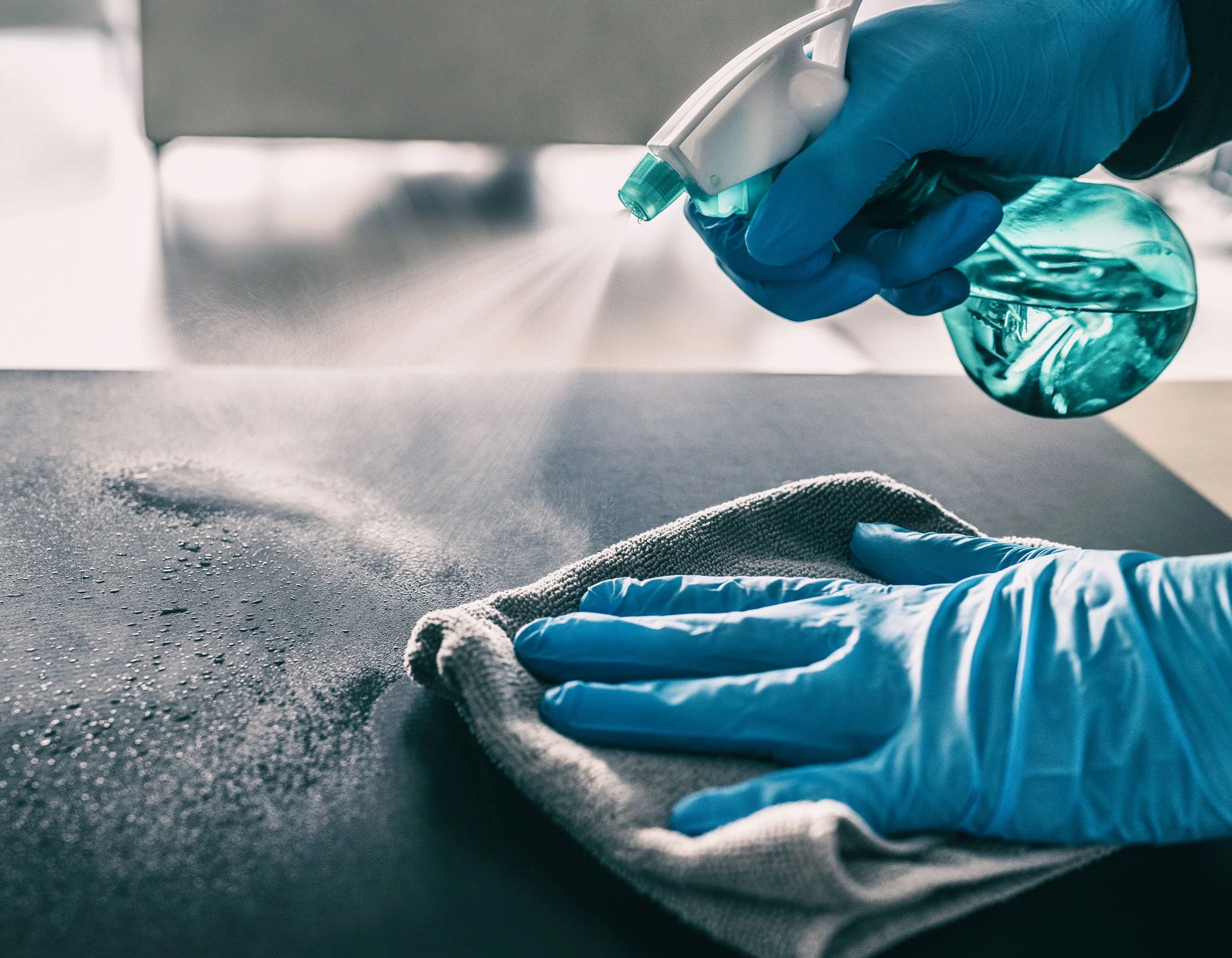 Gloved hands spraying a disinfectant