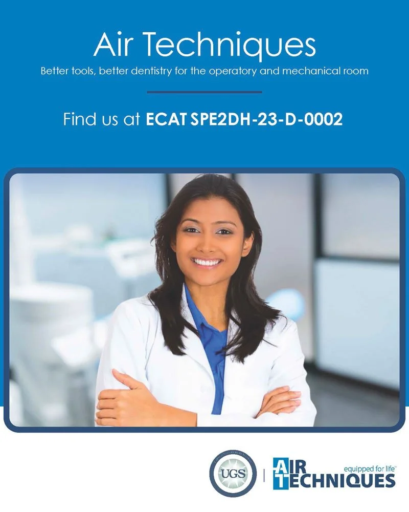 A smiling woman in a white lab coat standing in a dental clinic with dental equipment in the background.