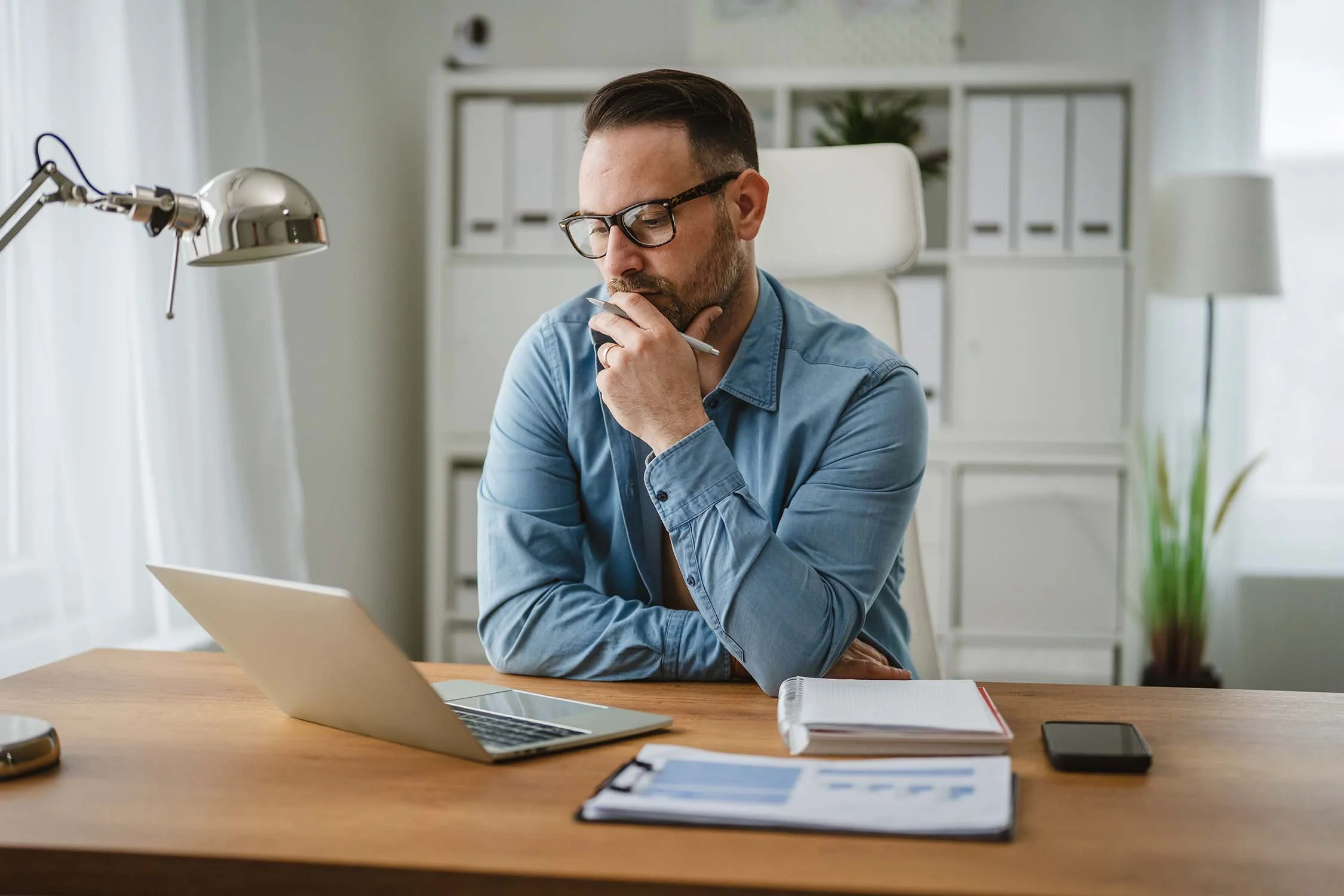 Man considering nonprofit executive director job description that he is reading on his laptop.