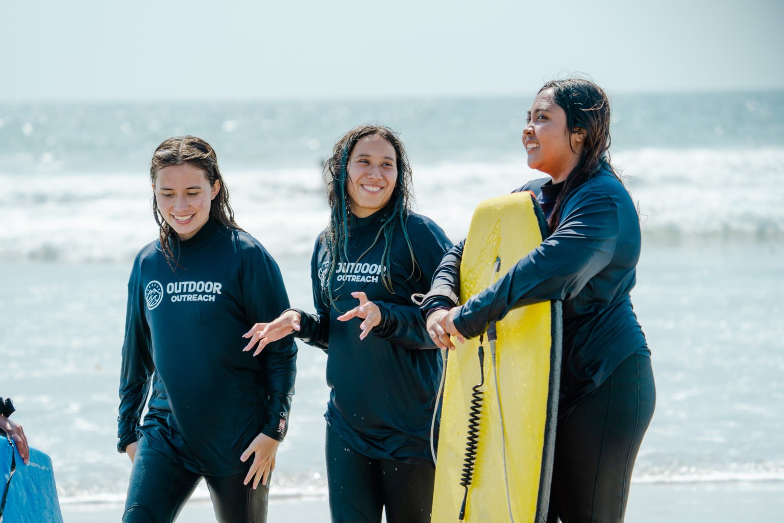 group-of-young-female-surfers-wearing-wetsuits-with-the-outdoor-outreach-logo-on-them.jpg