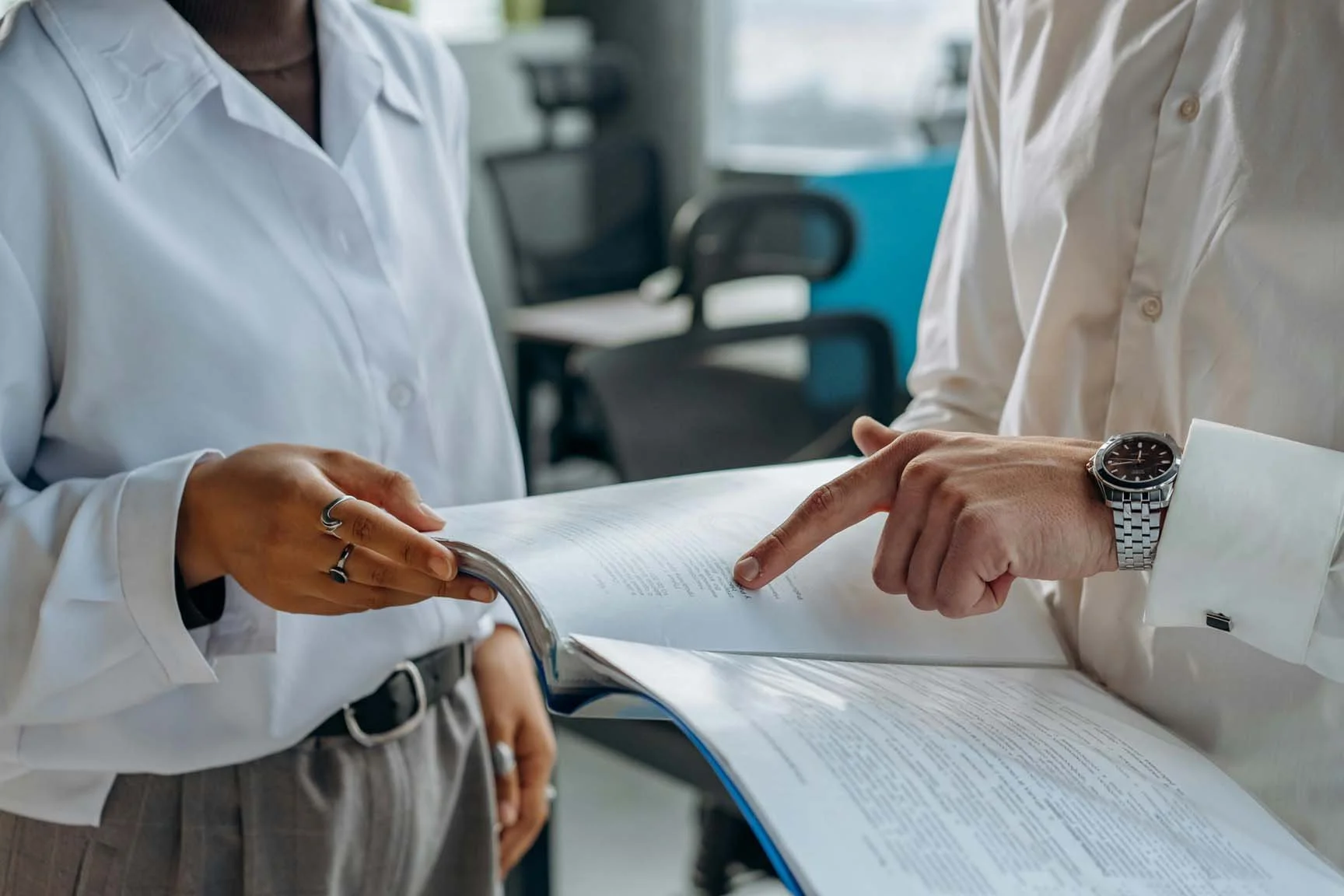 people standing in office discussing folder with printed documents