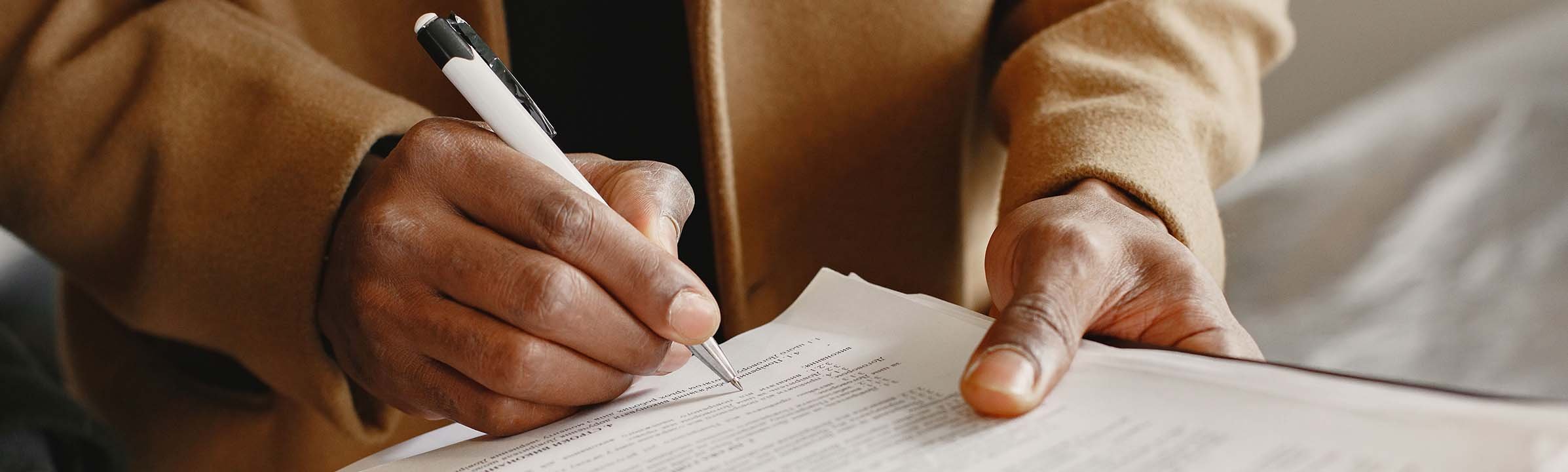 Nonprofit manager reviewing printed paperwork and making notes with a pen.