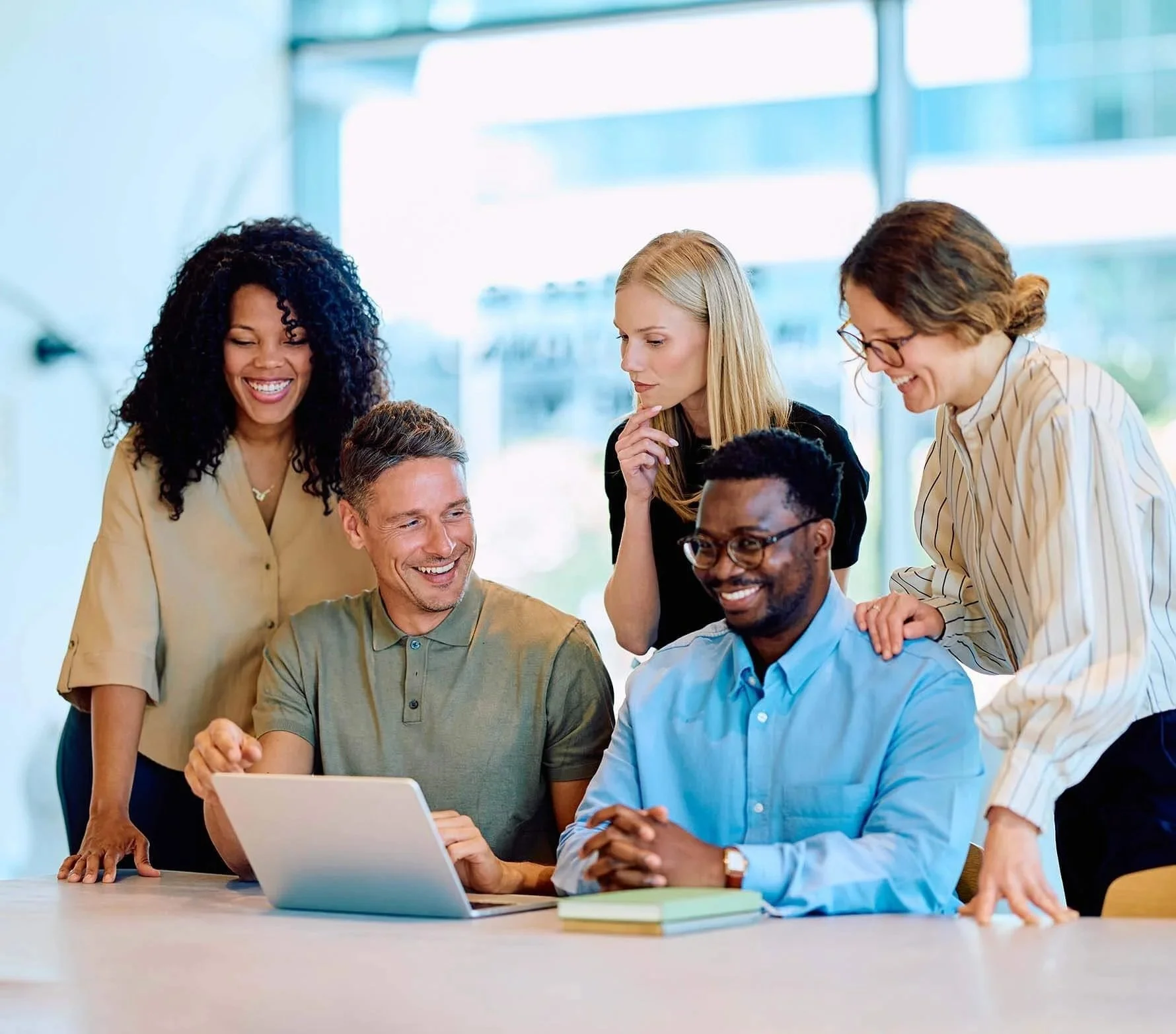 nonprofit leadership team working together and laughing with their fiscal sponsor at a table with a laptop and stack of books.