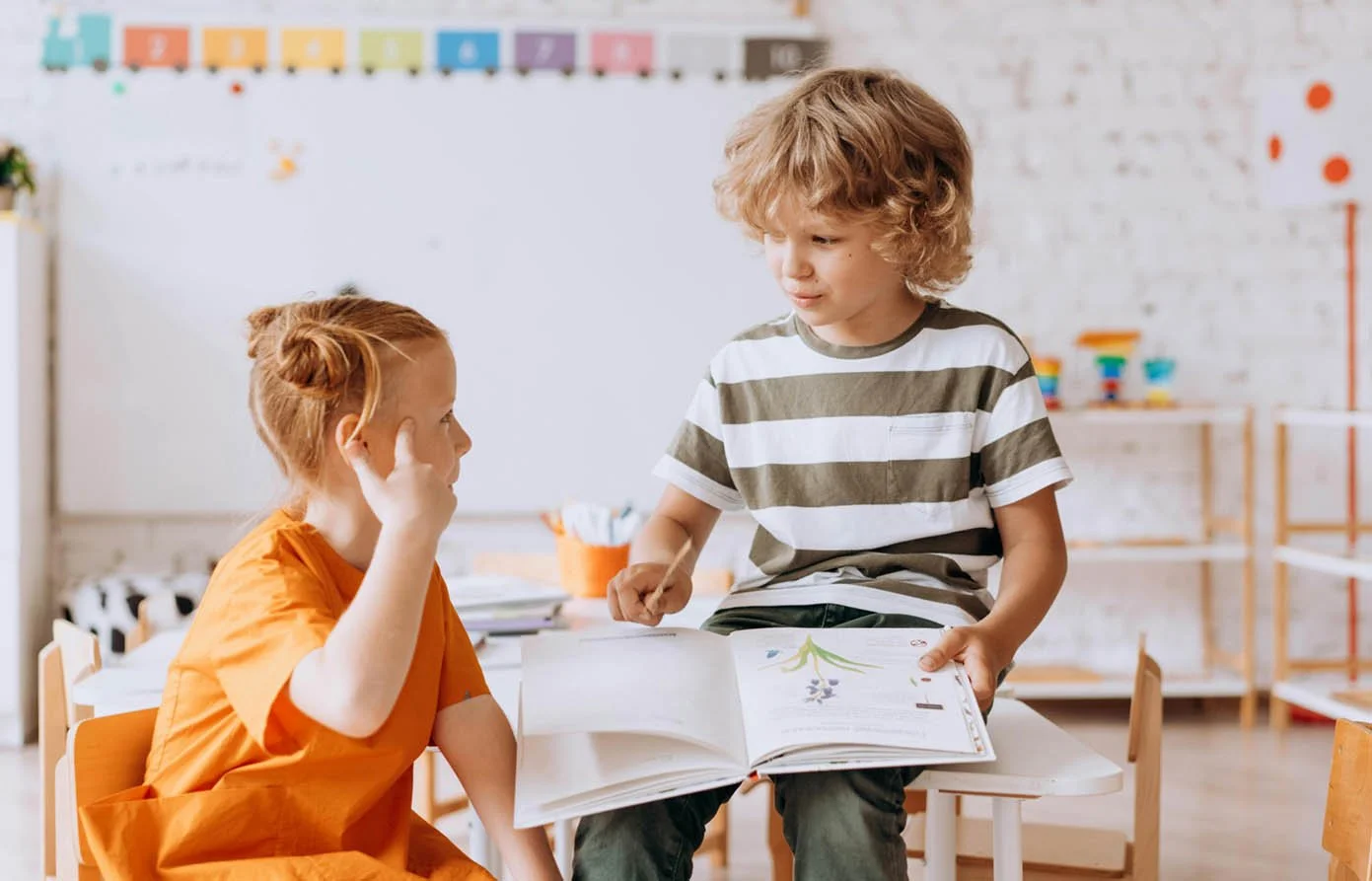 two kids reading picture book together in classroom