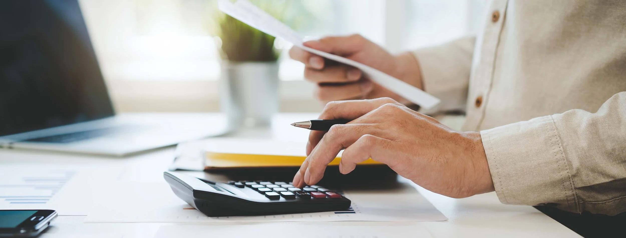 Man holding a receipt in one hand and typing on calculator with the other.