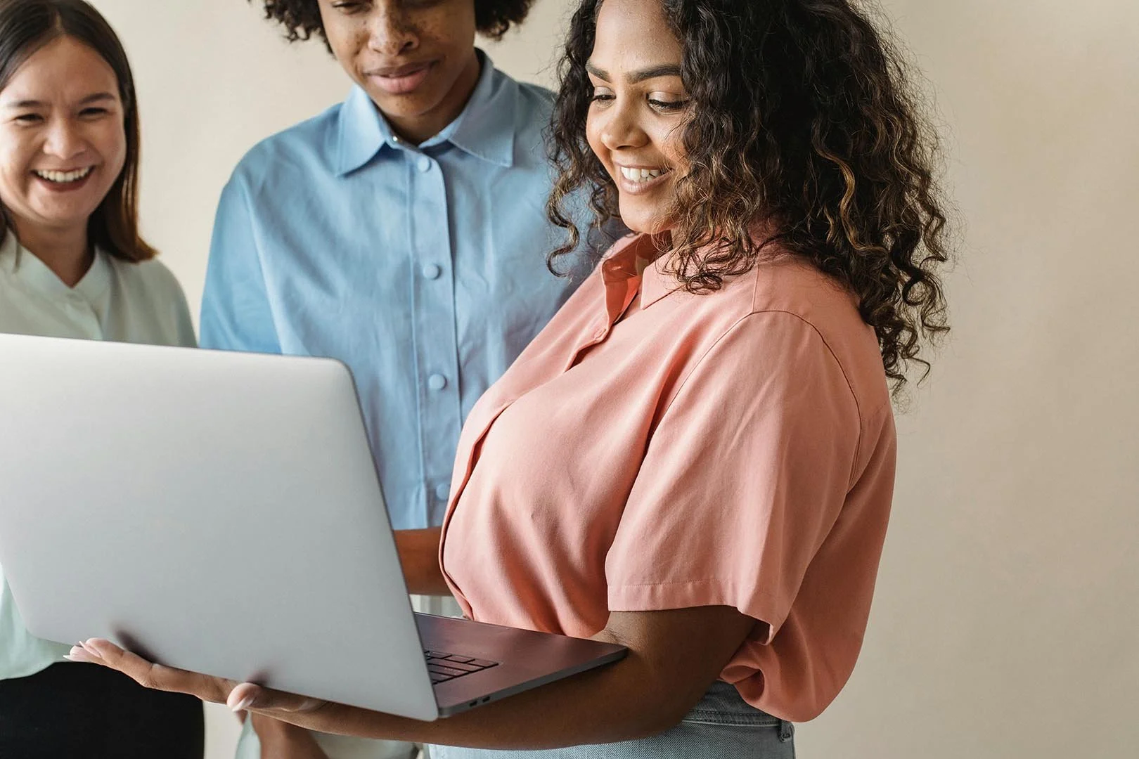 woman holding laptop and confidently showing her work to a couple of other coworkers