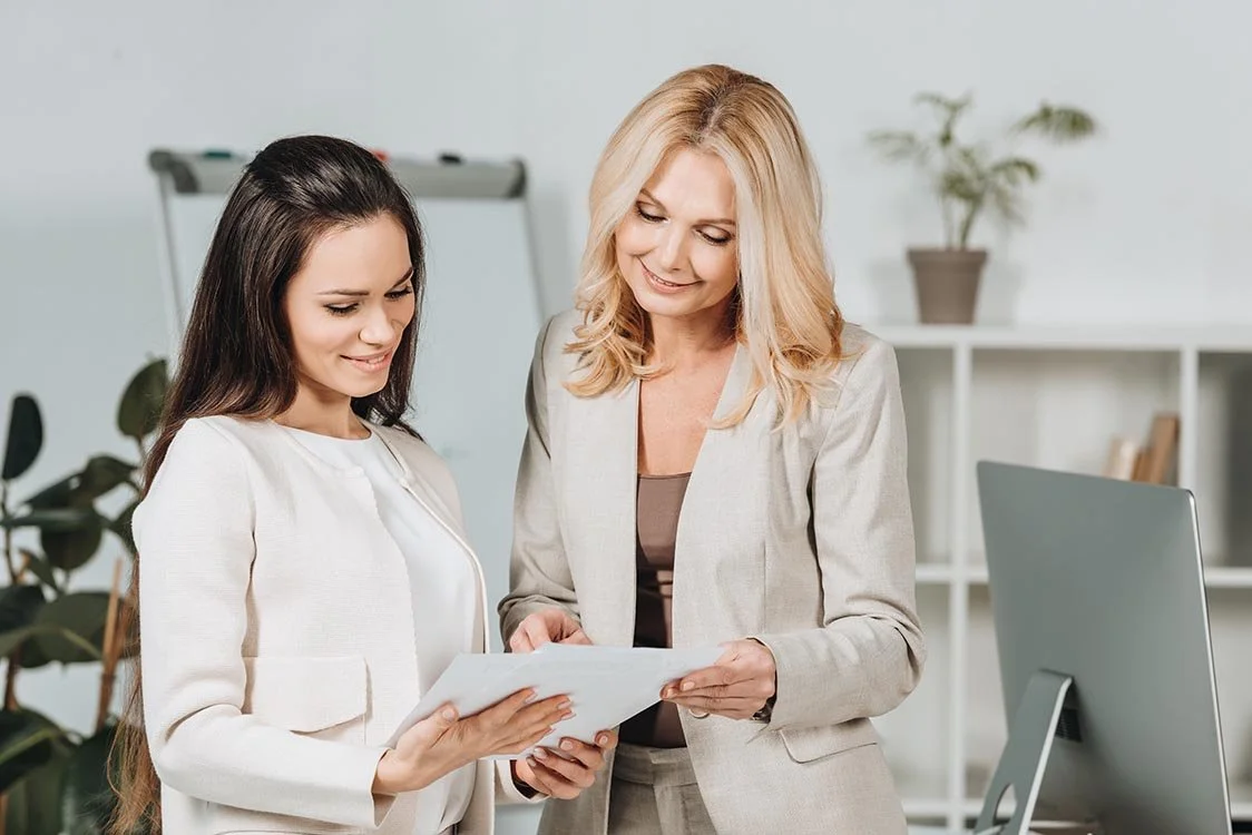 Nonprofit HR professional looks over printed paperwork that an employee is holding in her hands.
