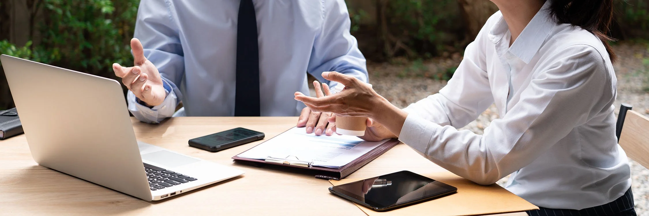 senior leaders wearing professional clothing discussing nonprofit policies over coffee at a table outside