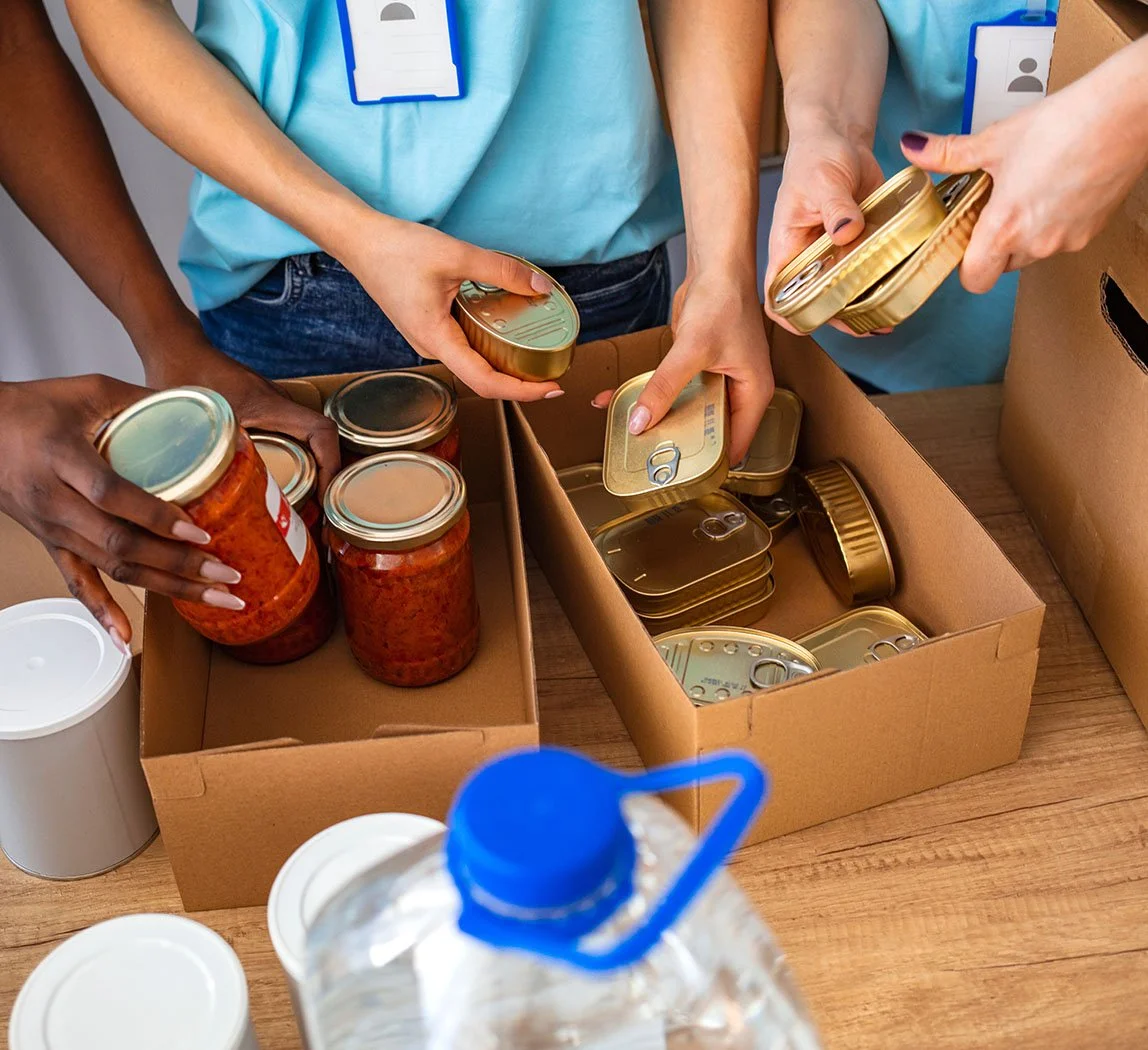 nonprofit volunteers wearing blue shirts filling up cardboard boxes with donated canned goods