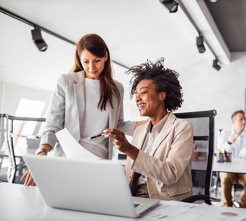 Team member enthusiastically reviewing a nonprofit accounting report with female manager wearing a grey blazer.