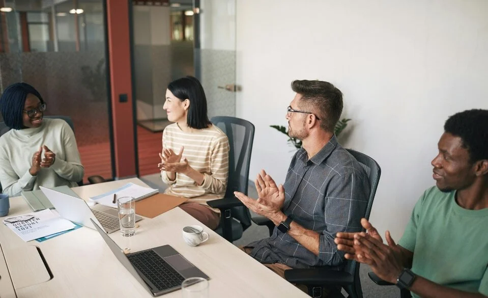 nonprofit board sitting at long table with members smiling and clapping