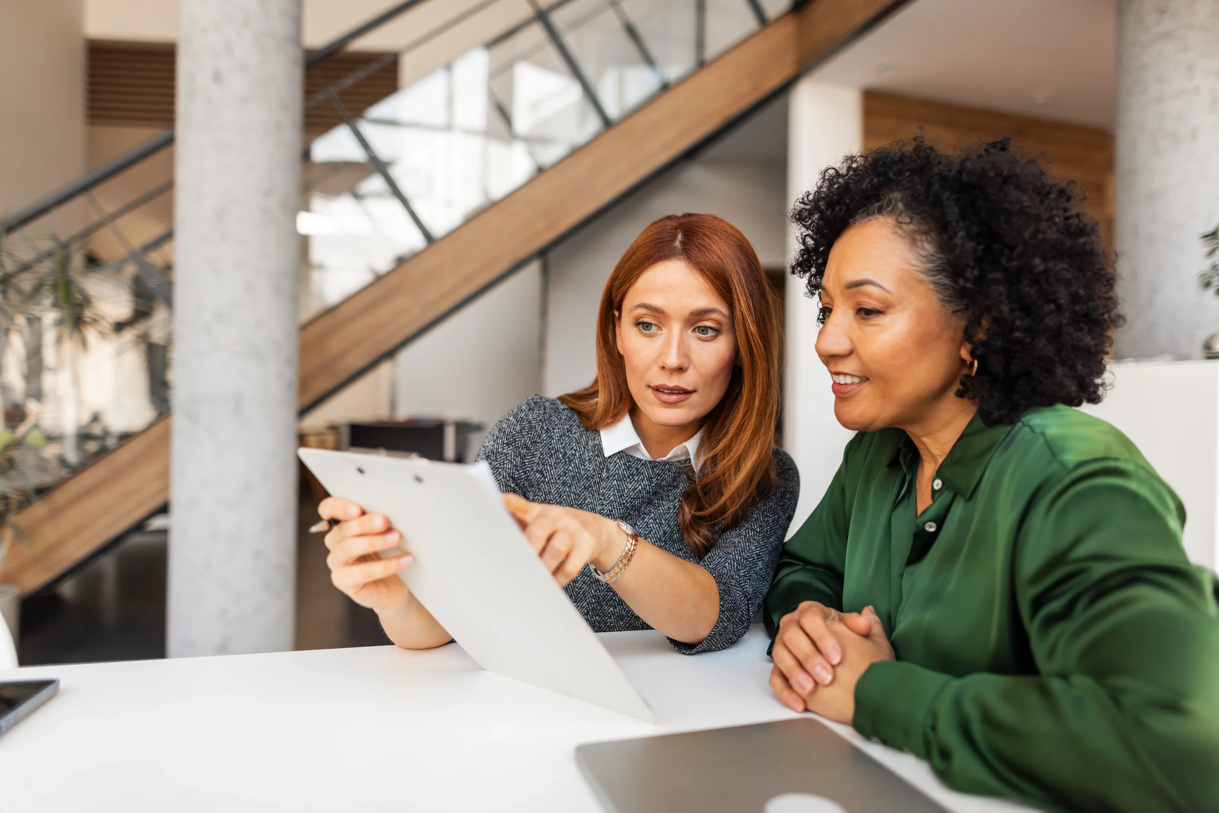 HR expert guiding nonprofit leader through filling out paperwork in modern office setting
