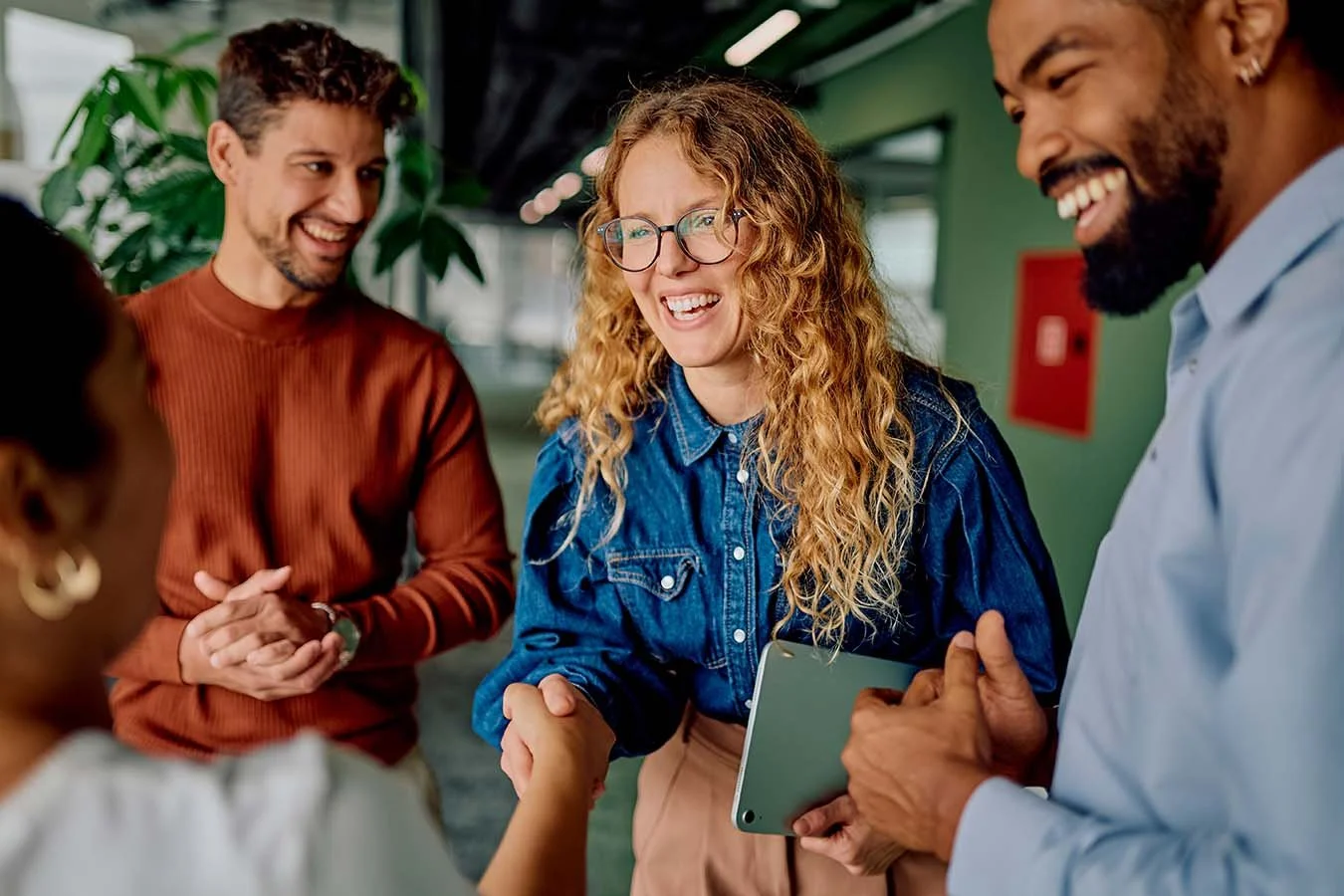 friendly nonprofit employees welcoming new hr consultant in the hallway and shaking hands