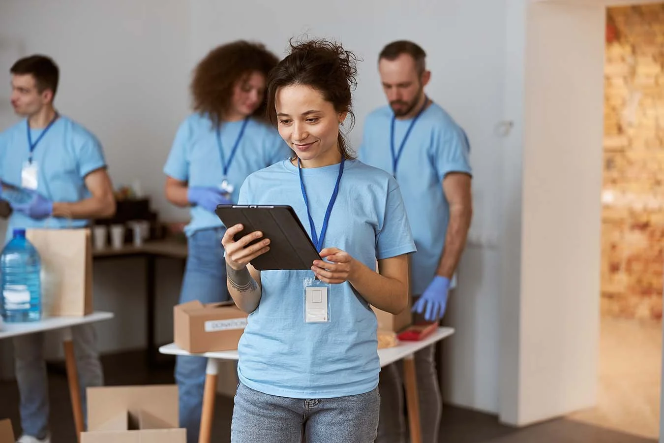 nonprofit team member wearing a t-shirt with a badge reviews a tablet at volunteer event