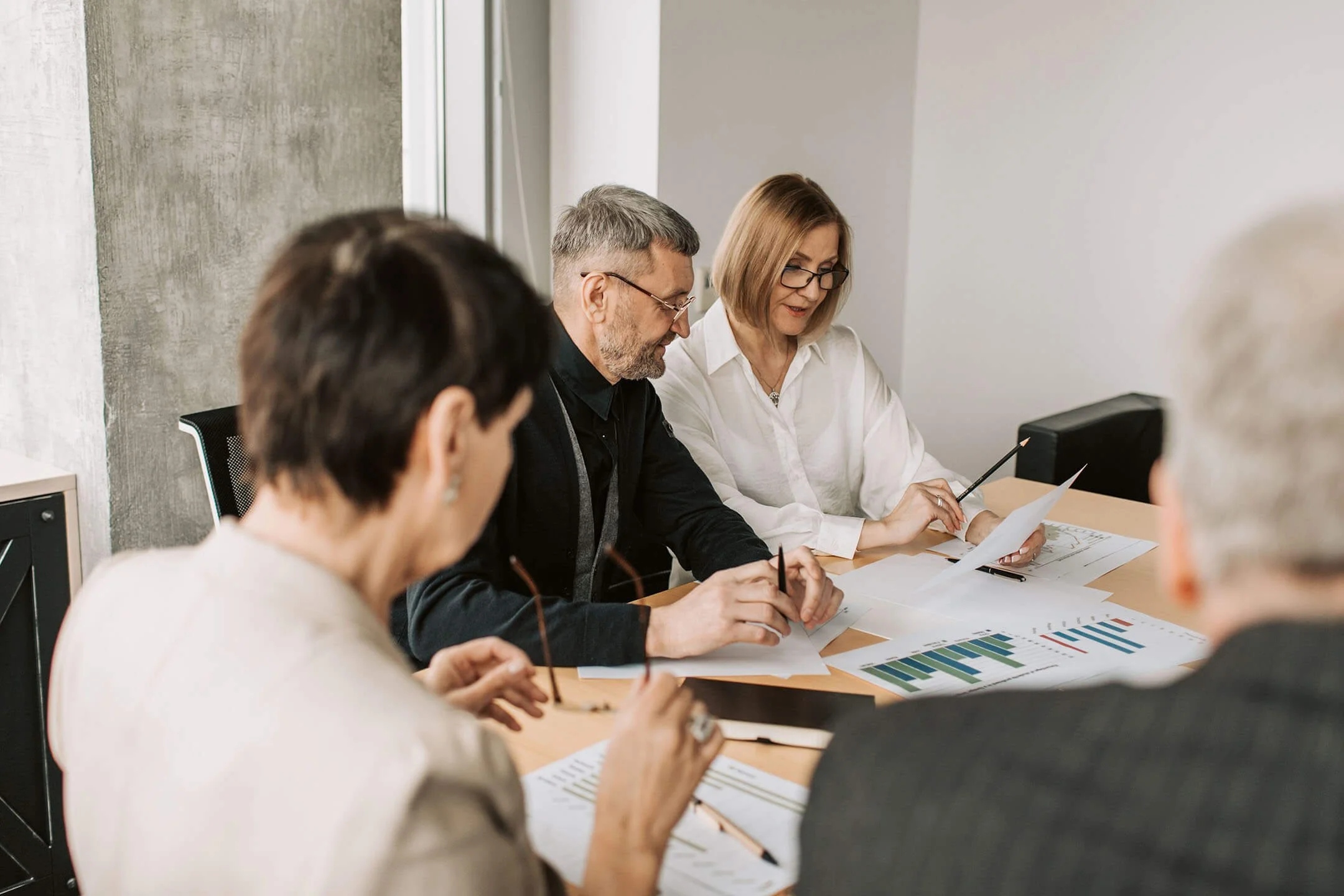Nonprofit board members review accounting reports and compare printed charts.