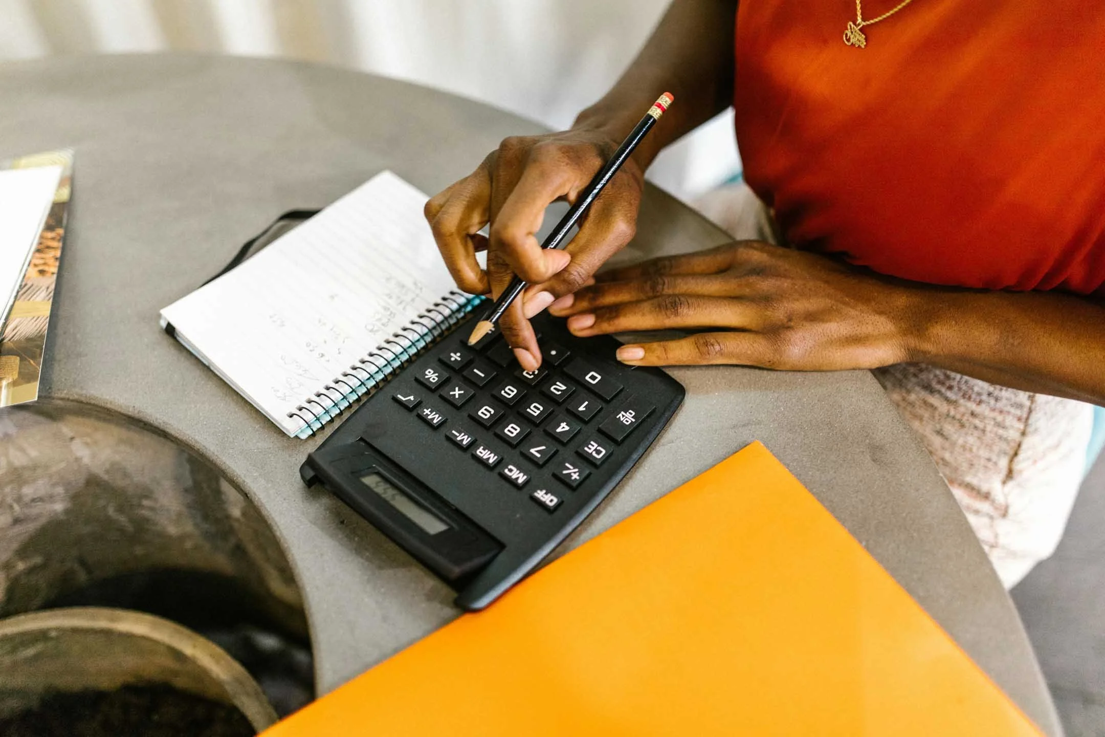 woman calculating budget with a calculator at her desk.