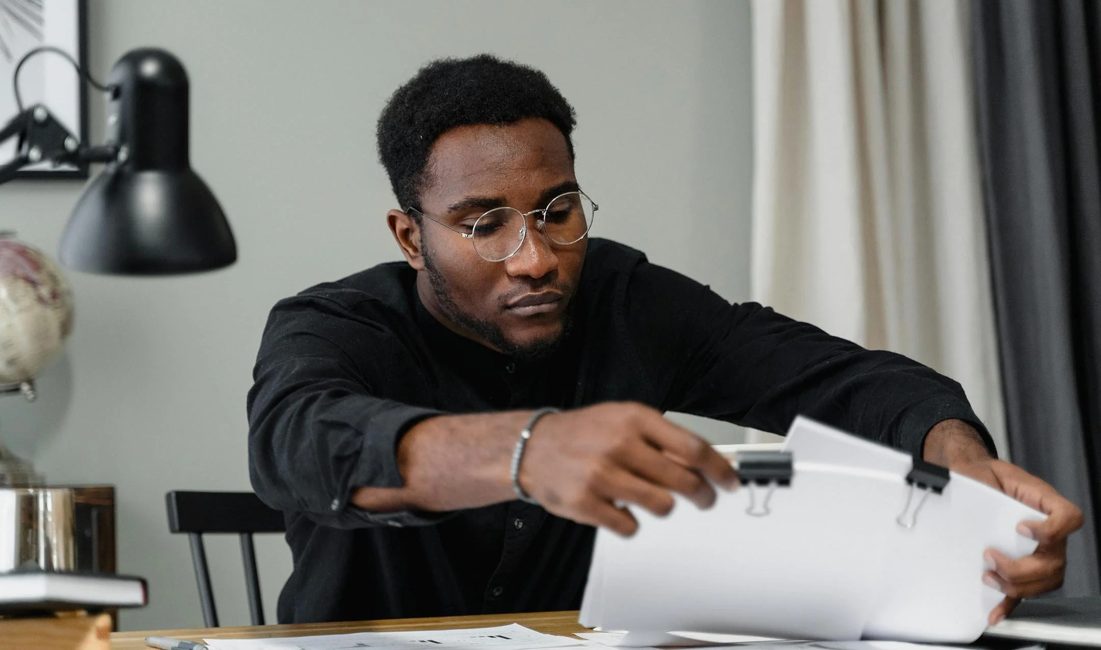 Man working at desk organizing stacks of paper clipped together