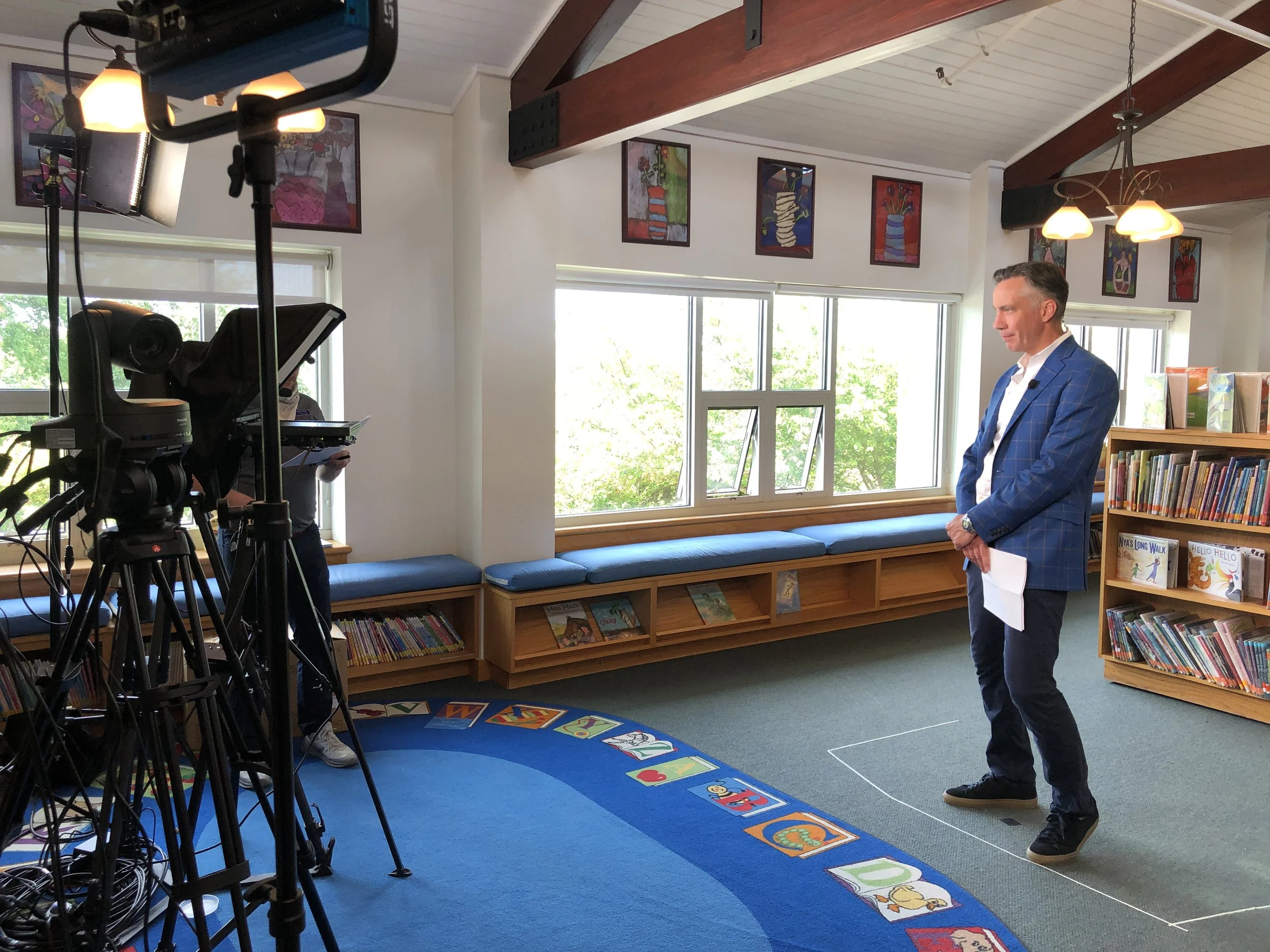Man in children's library in front of the camera during a broadcast auction event in 2020. Event produced by Washington D.C. based event production company Stratus Firm