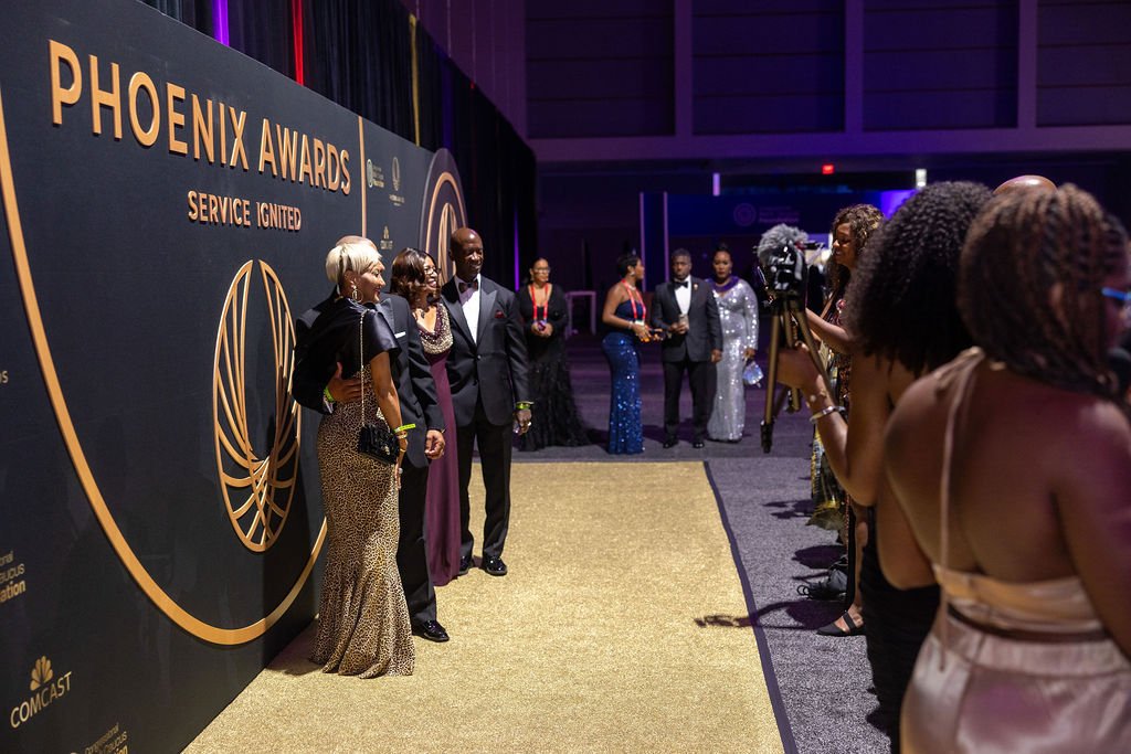 Guests having their photo taken in front of the Phoenix Awards step and repeat during the CBCF Annual Legislative Conference 2025