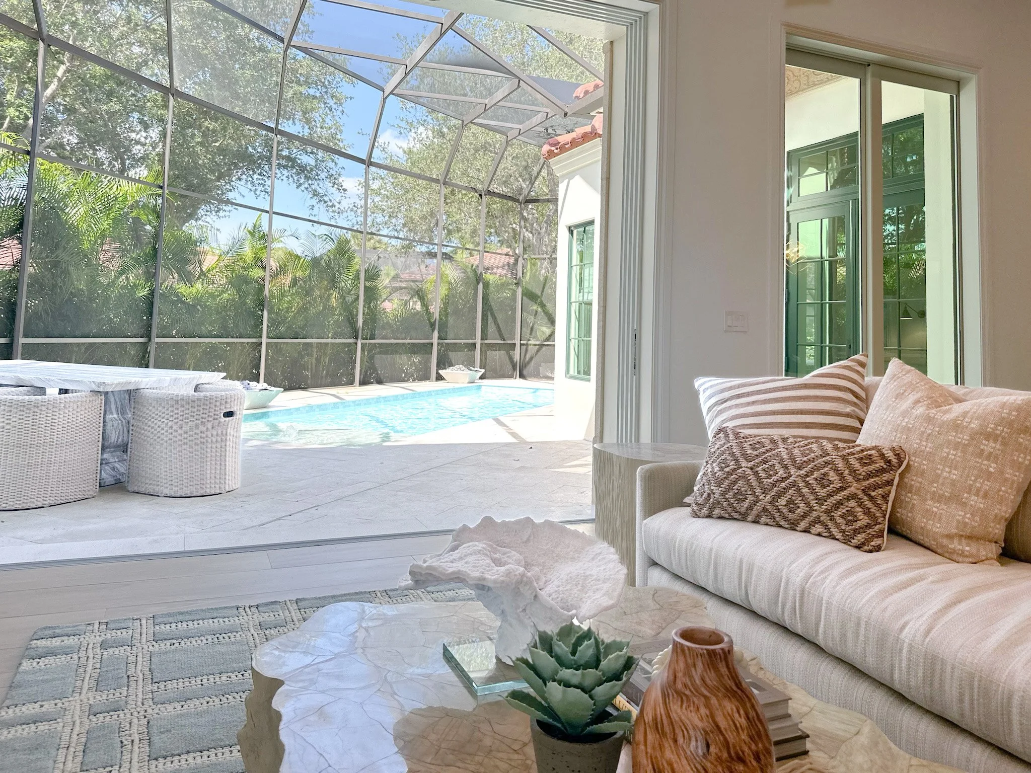 Lark and Soul interior design- indoor/outdoor living. Family room with large sliding doors opening to the pool in Naples Florida.