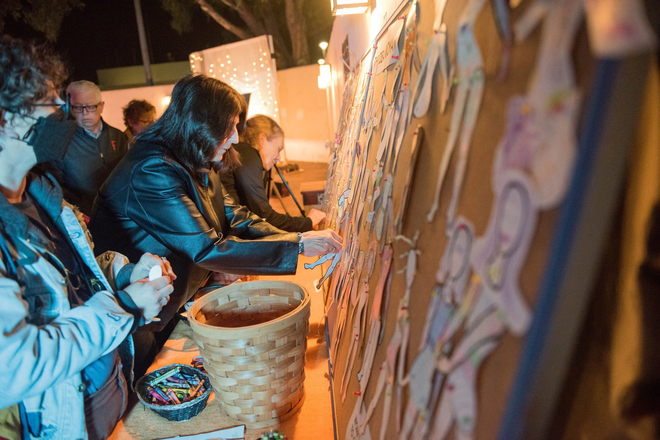 People at a virtual or physical event creating and decorating paper cutouts of reindeer on a large bulletin board.