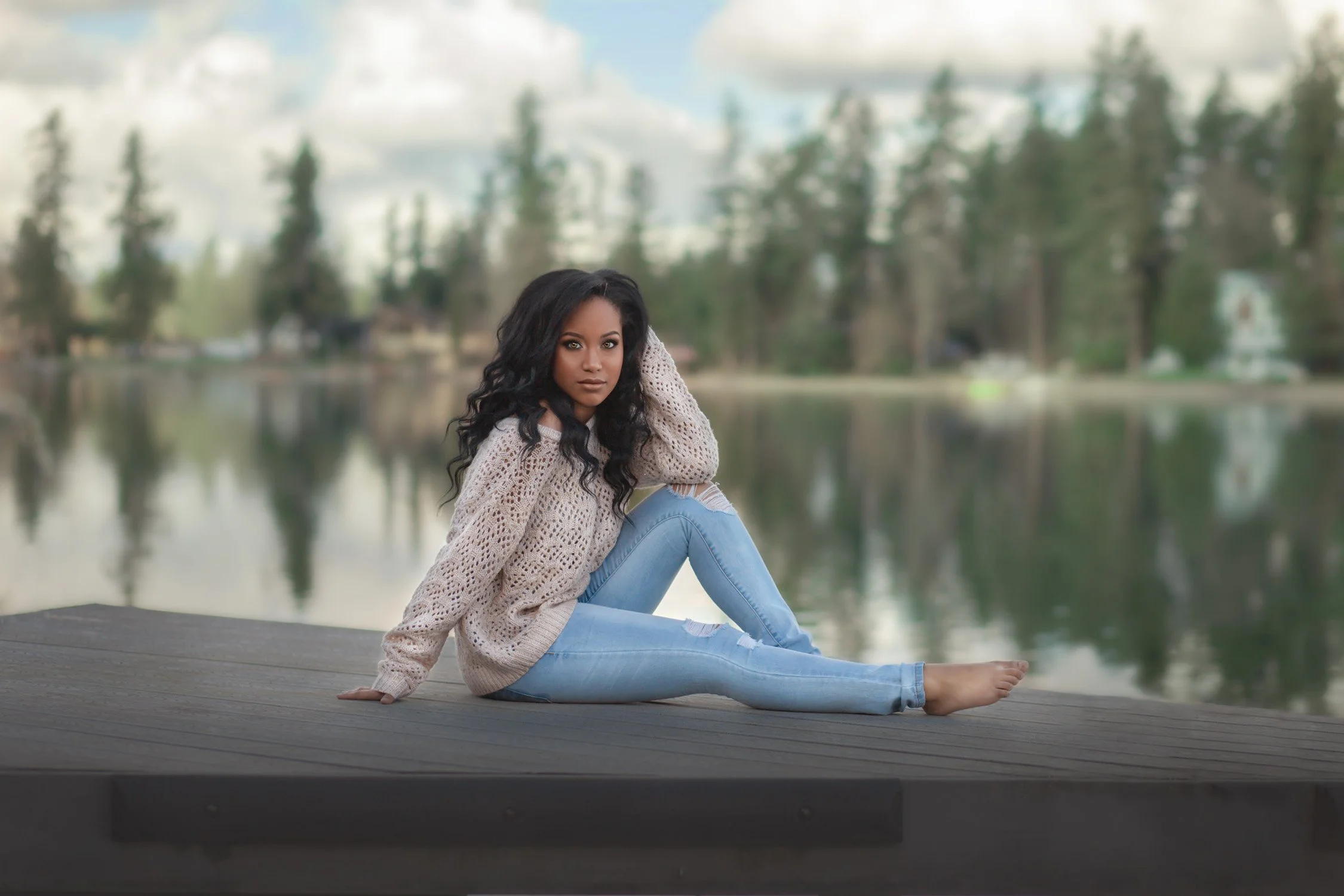 Woman in jeans and a cream sweater posing outdoors during a casual portrait and boudoir photography session.