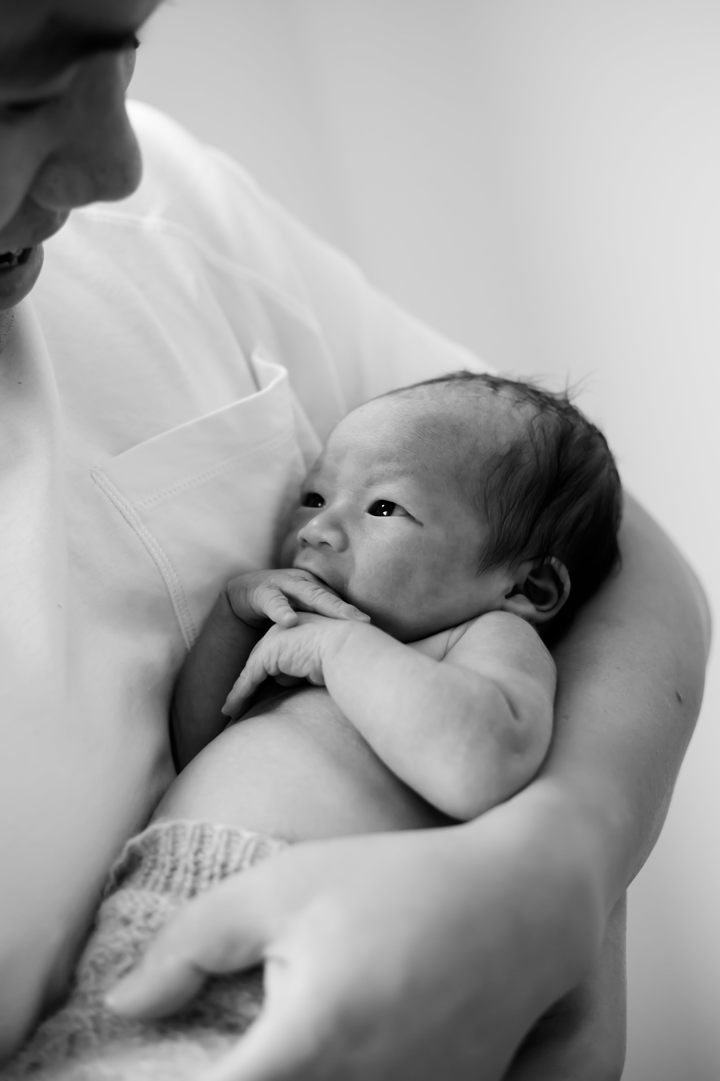 Newborn baby laying peacefully in dads arms during a Fresh 48 newborn photography session in Geelong