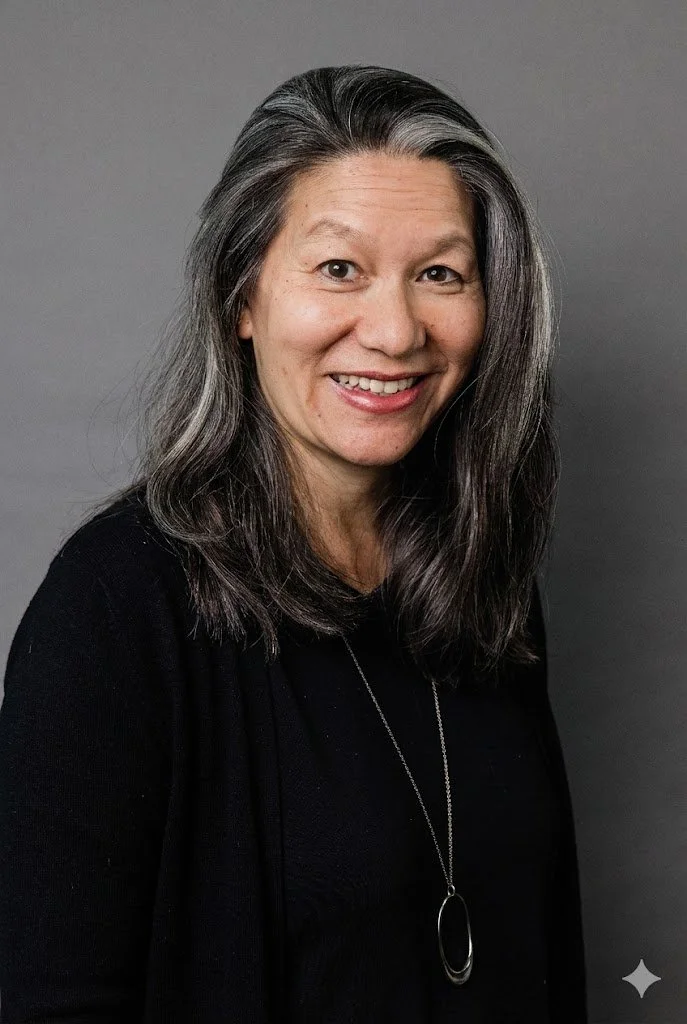 Tasha is smiling against a grey backdrop. She is wearing a black shirt.