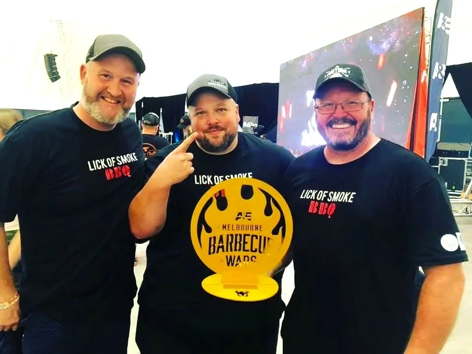 Three men in black tshirts smiling