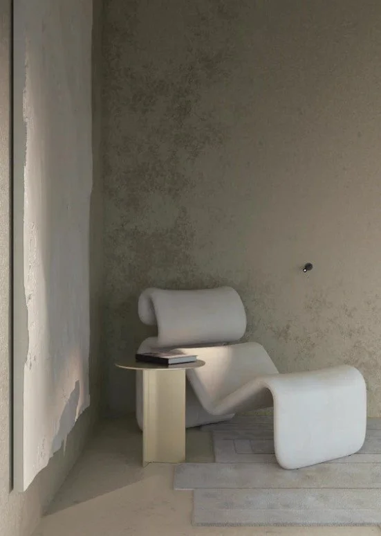 Moderne designersofa i hvid, stilfuld og kurvet, placeret i et minimalistisk rum med betonvægge og et lille sidebord.