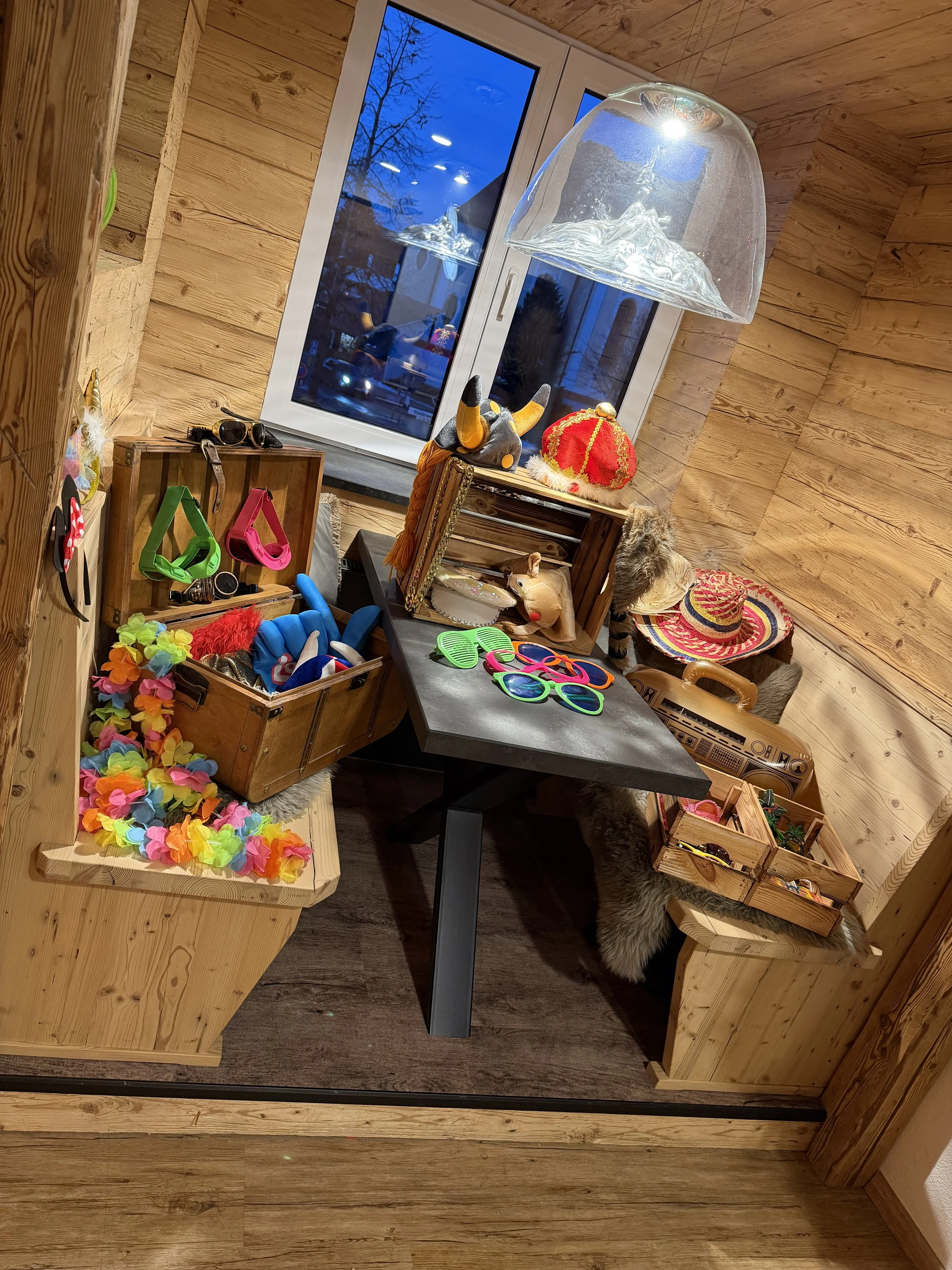 Ein kleines, gemütliches Zimmer mit Holzvertäfelung, gefüllt mit buntem Partyzubehör, Dekorationen, Spielsachen und Accessoires.