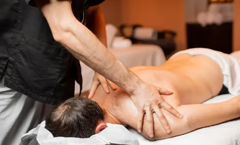 Person receiving a back massage on a massage table with cloths covering the lower body in a massage room.