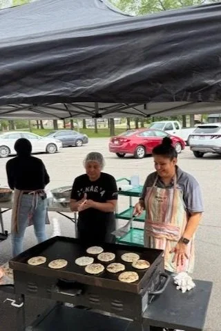 Conagra volunteers cooking pupusas on an outdoor griddle.