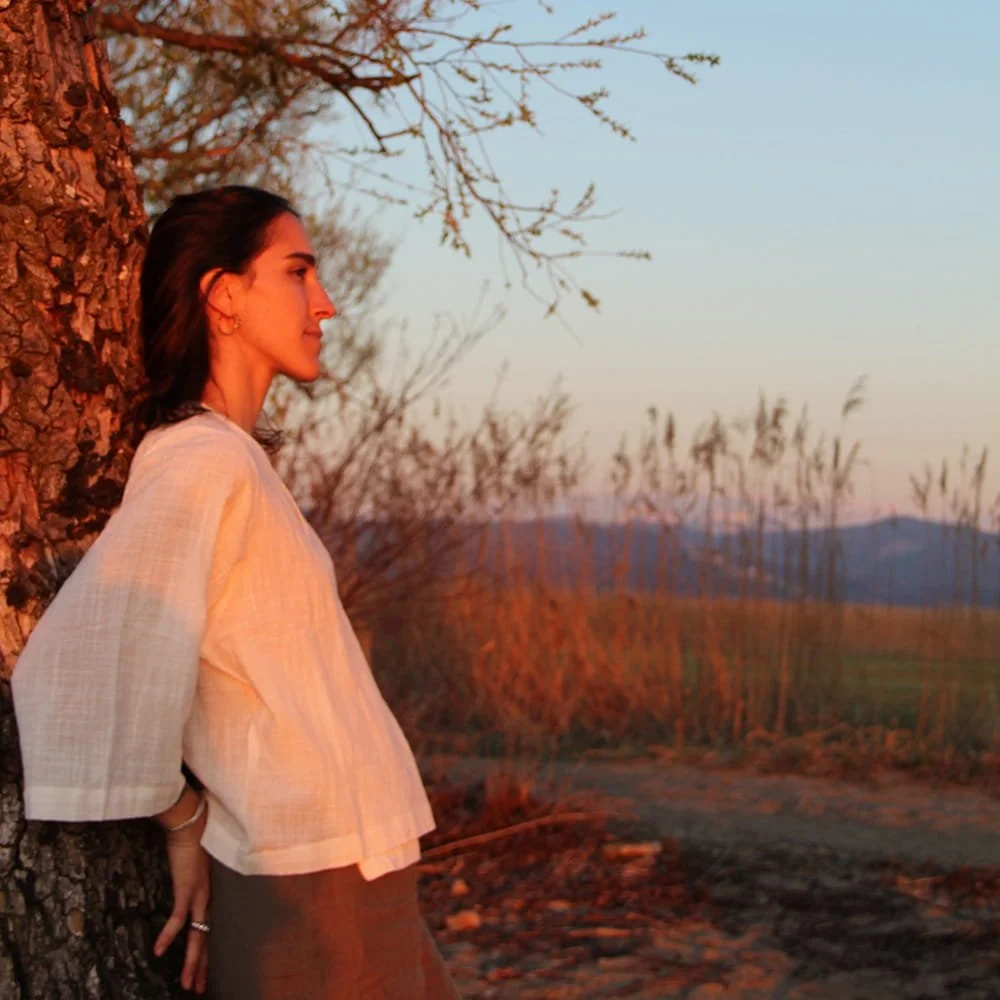 Jil Bianca leaning against a tree at sunset, illustrating her mindful approach to holistic identity, mind and body integration.