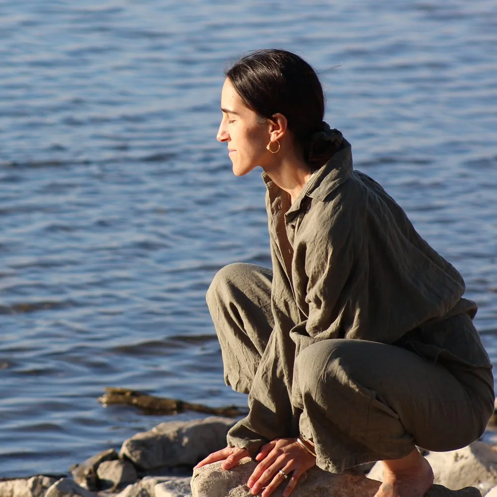 Jil Bianca meditating by the water, representing breathwork practice for stress release, clarity and inner wisdom.