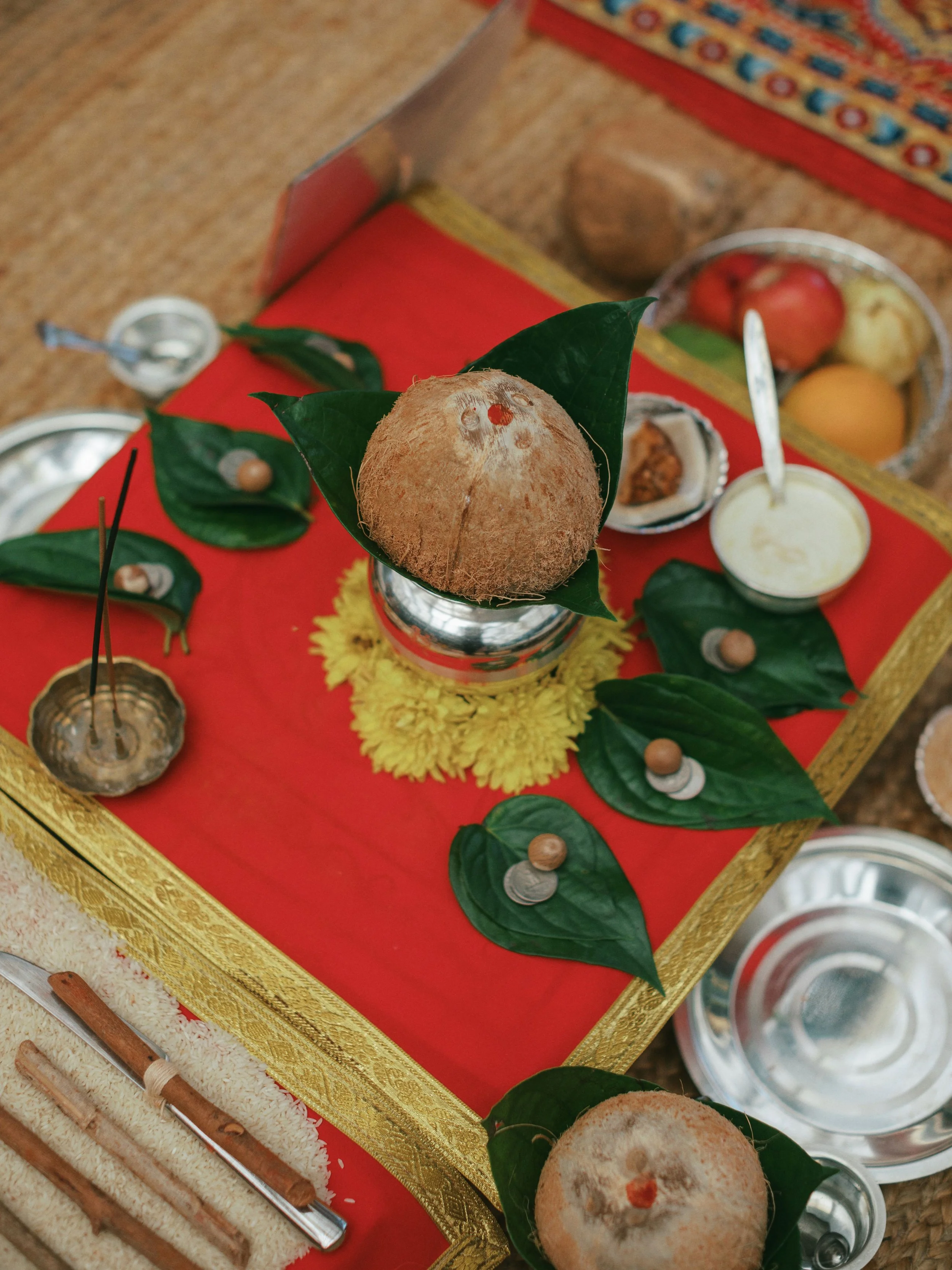 Hindu religious offerings with coconuts, leaves, and ceremonial items on a decorated table.