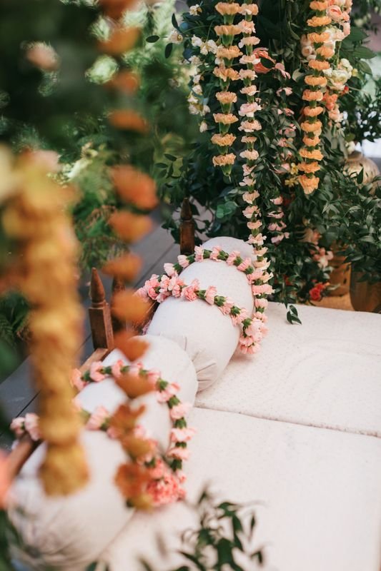 Decorative floral arrangements with pink and cream flowers around a cream-colored sofa, set in a garden or outdoor setting.