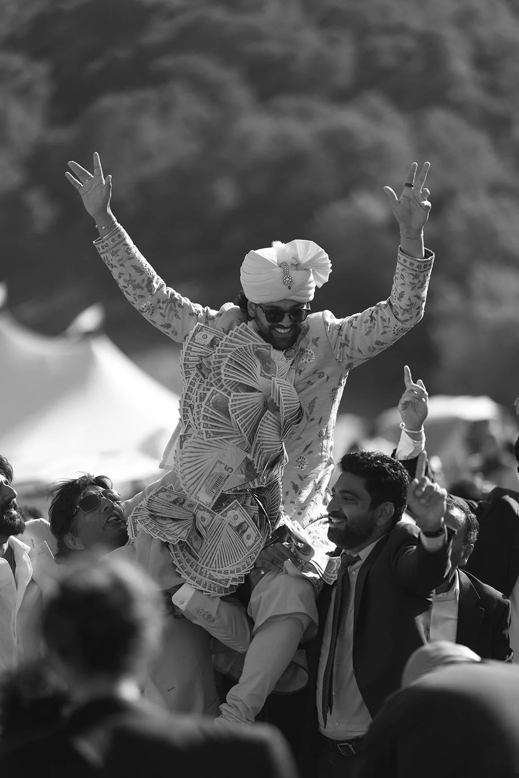 A man celebrating with a large amount of money, raised in the air, surrounded by people at an outdoor event.