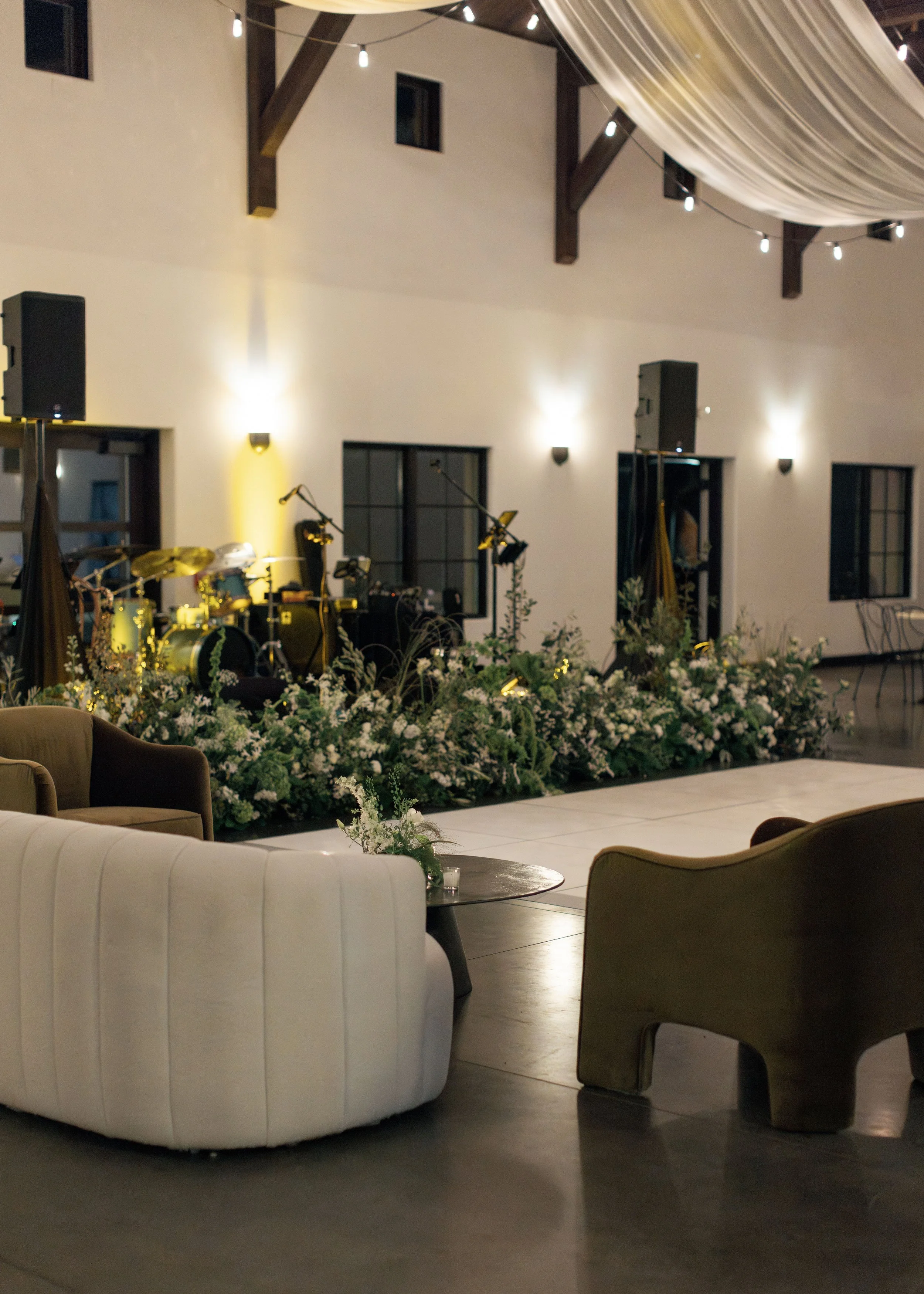 Indoor event space with a music stage and floral decorations in the foreground.